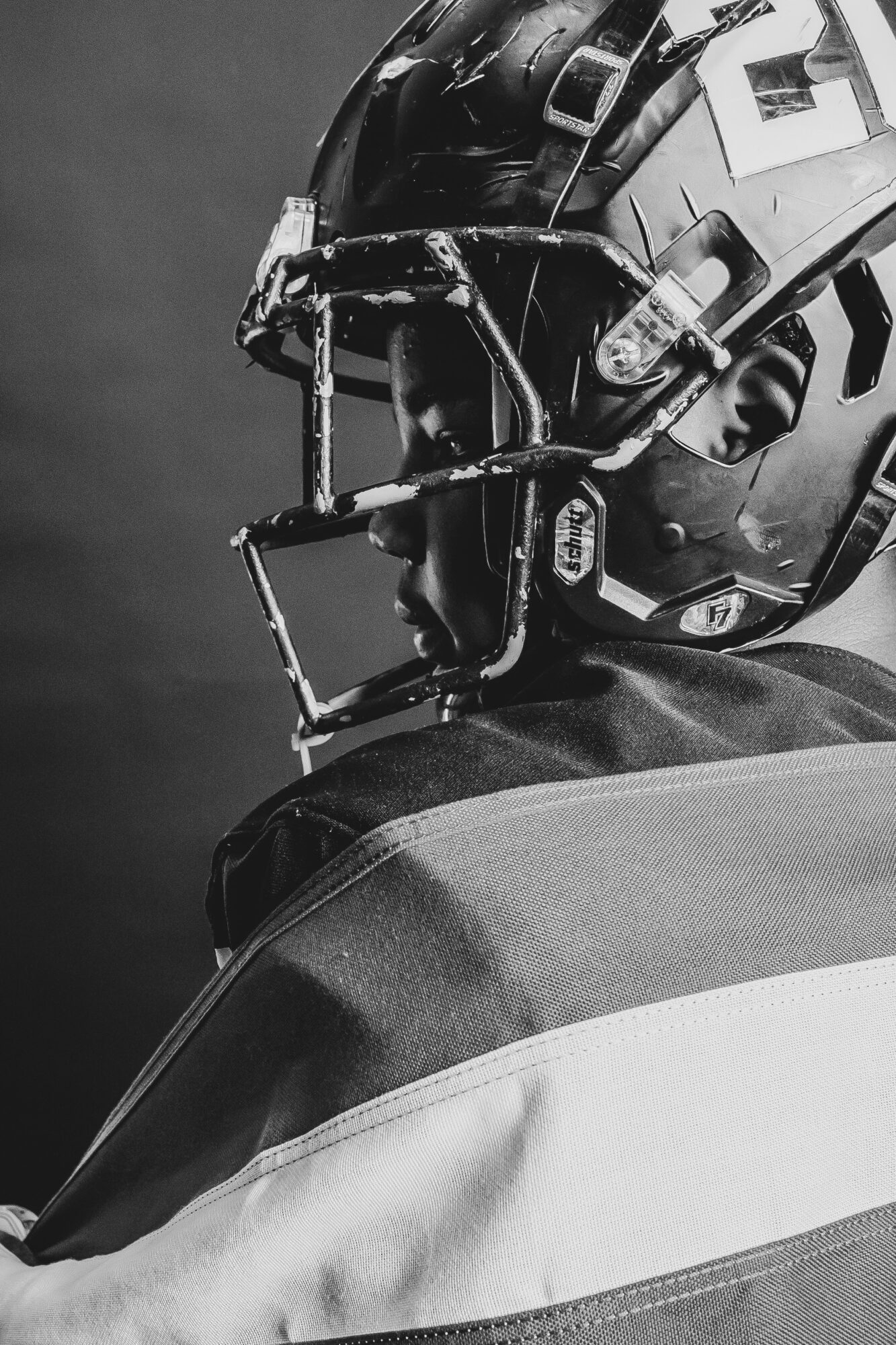 Close-up of a football player wearing a helmet and shoulder pads, facing sideways.