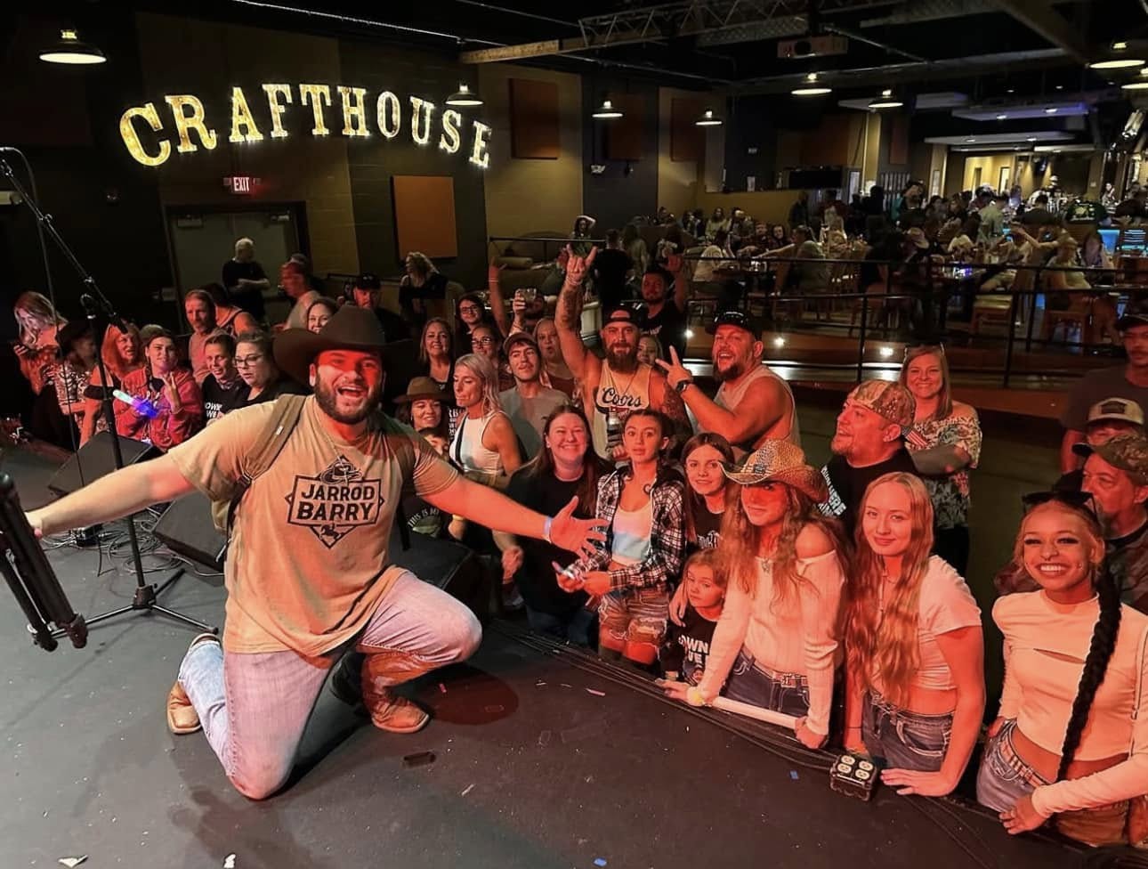 Group of children and adults on stage at Crafthouse, smiling and posing for a photo.