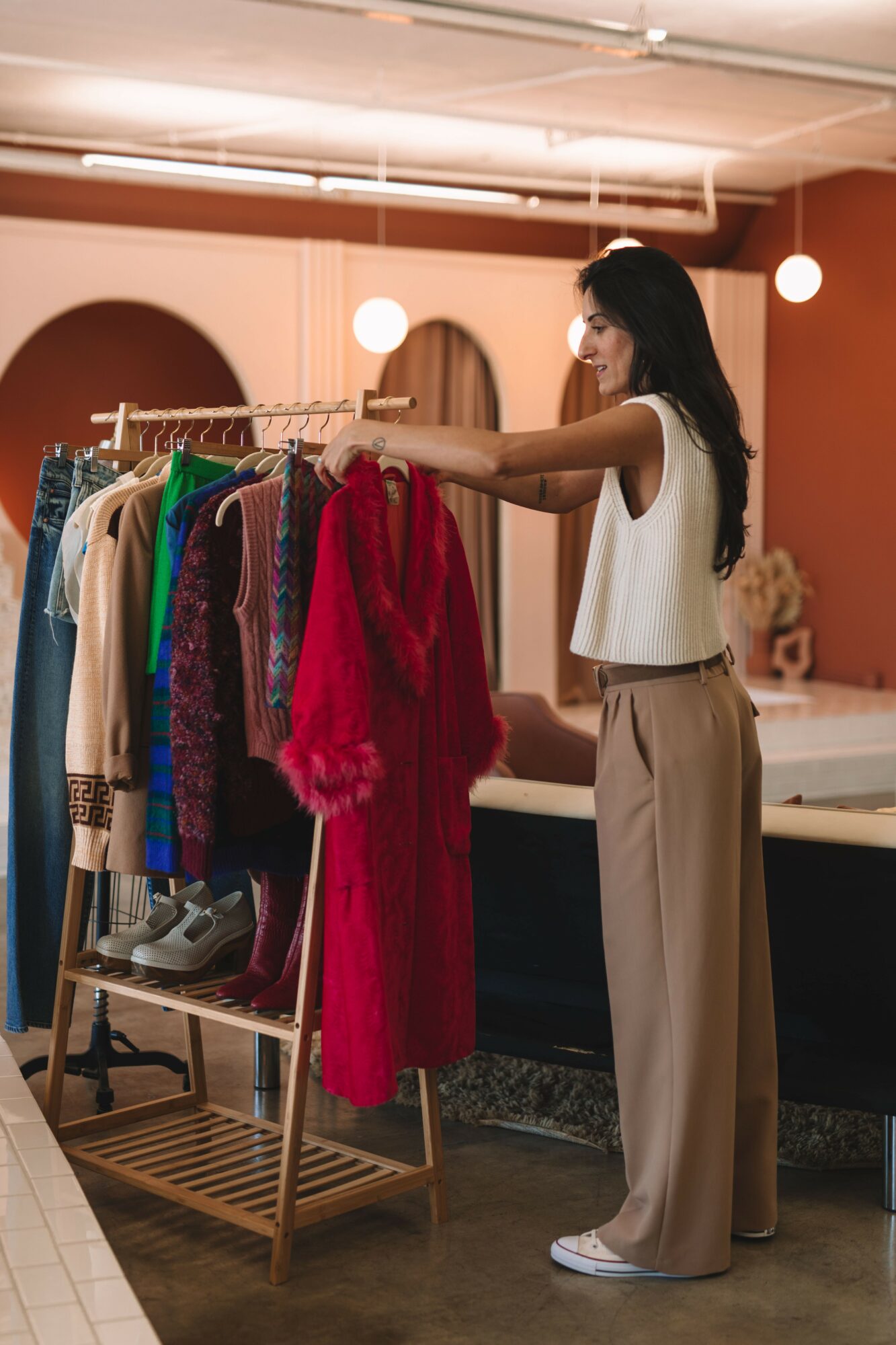 Woman browsing colorful dresses on a clothing rack in a boutique store.