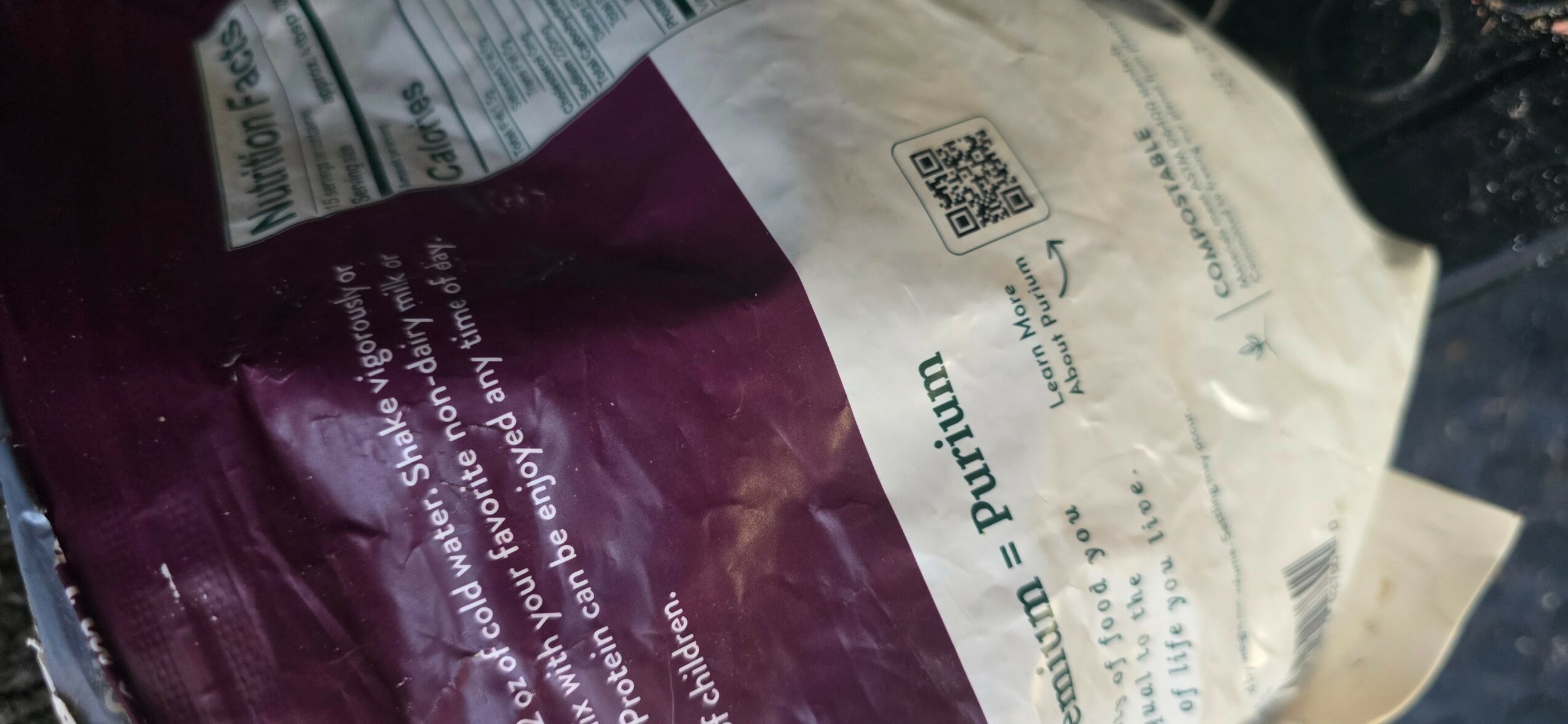 Close-up of a crumpled bag with purple and white sections, printed text, and a QR code.