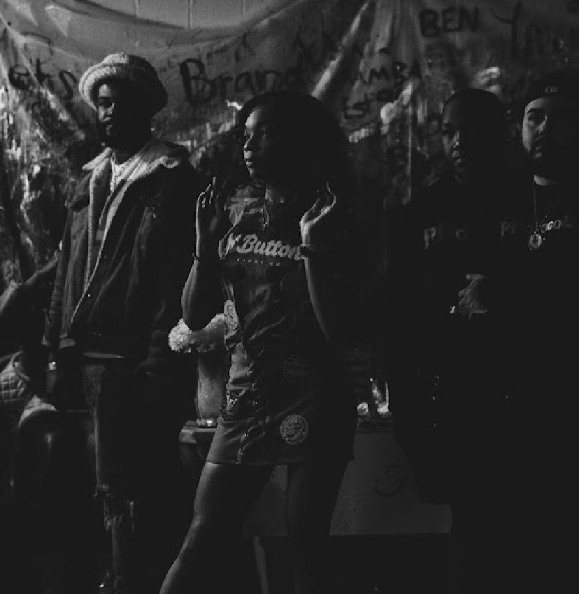 Group of four people standing outdoors at night, with a banner in the background, in black and white.