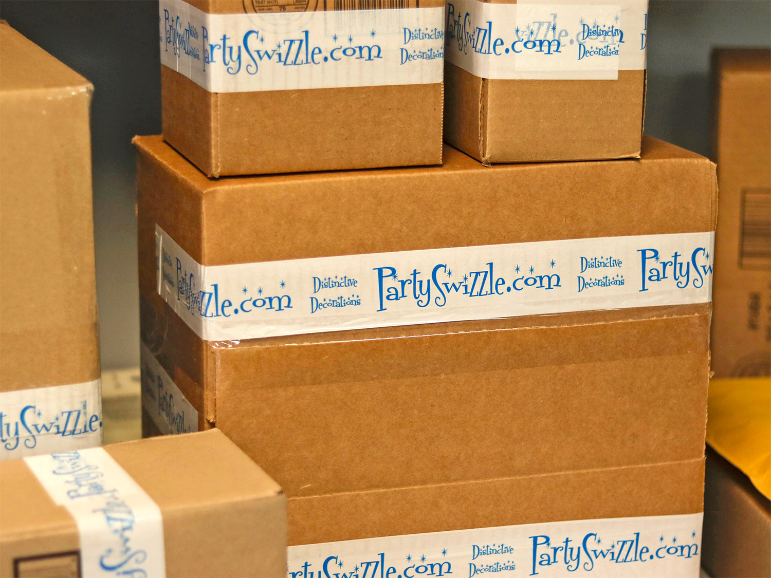 Stack of cardboard boxes with PartySwizzle.com tape, some boxes are larger and some smaller.