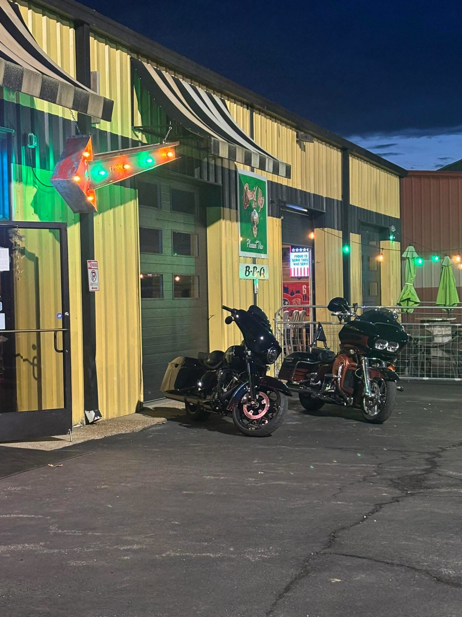 Two motorcycles parked outside a colorful building with green, yellow, and black vertical stripes, under a dark sky.