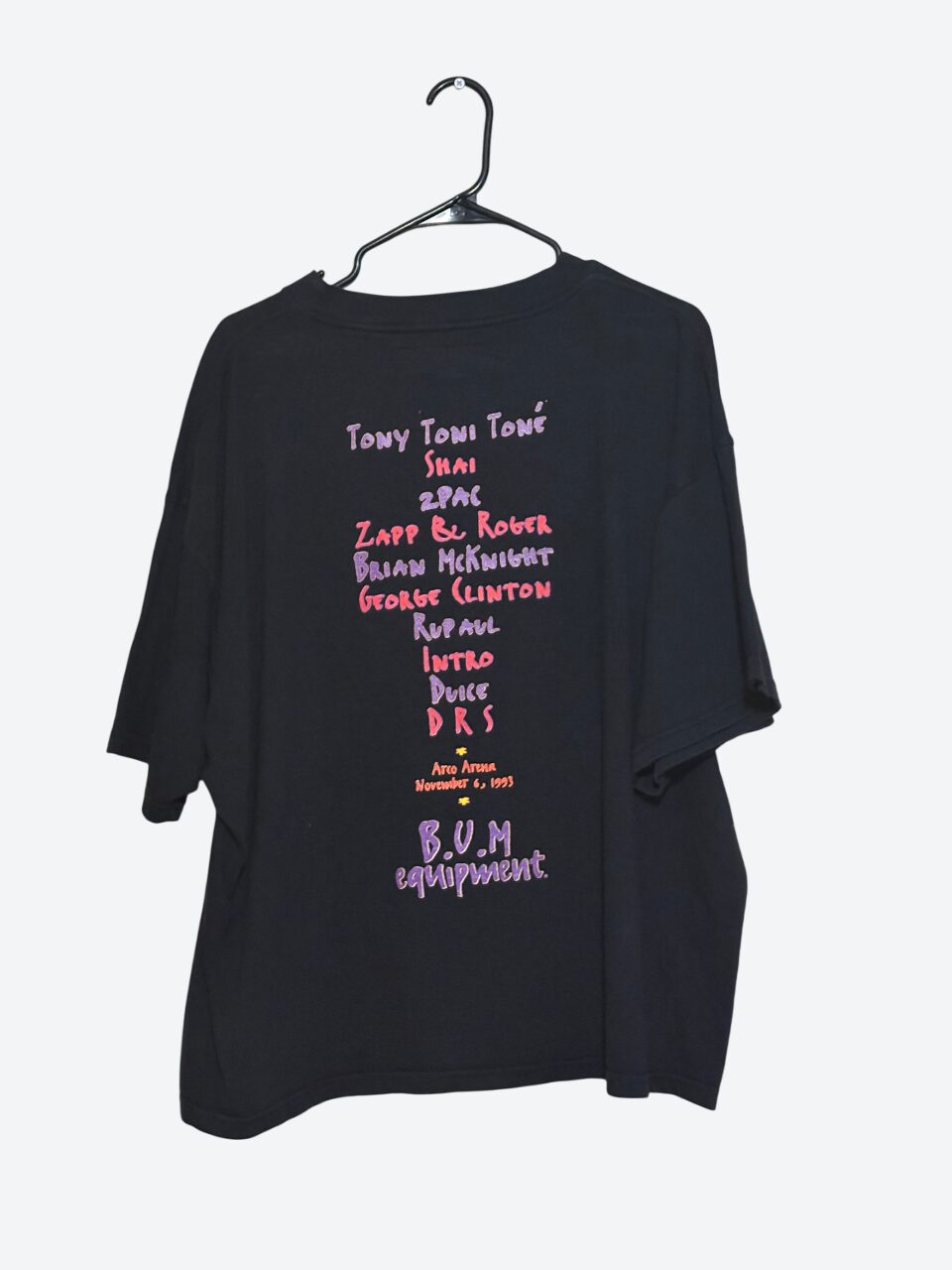 Black T-shirt with colorful text and graphics hanging on a hanger against a white background.