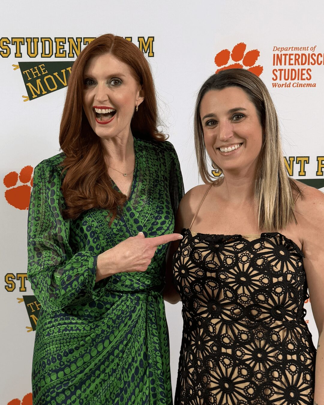 Two women standing together, smiling, with a backdrop featuring logos and text related to film studies.