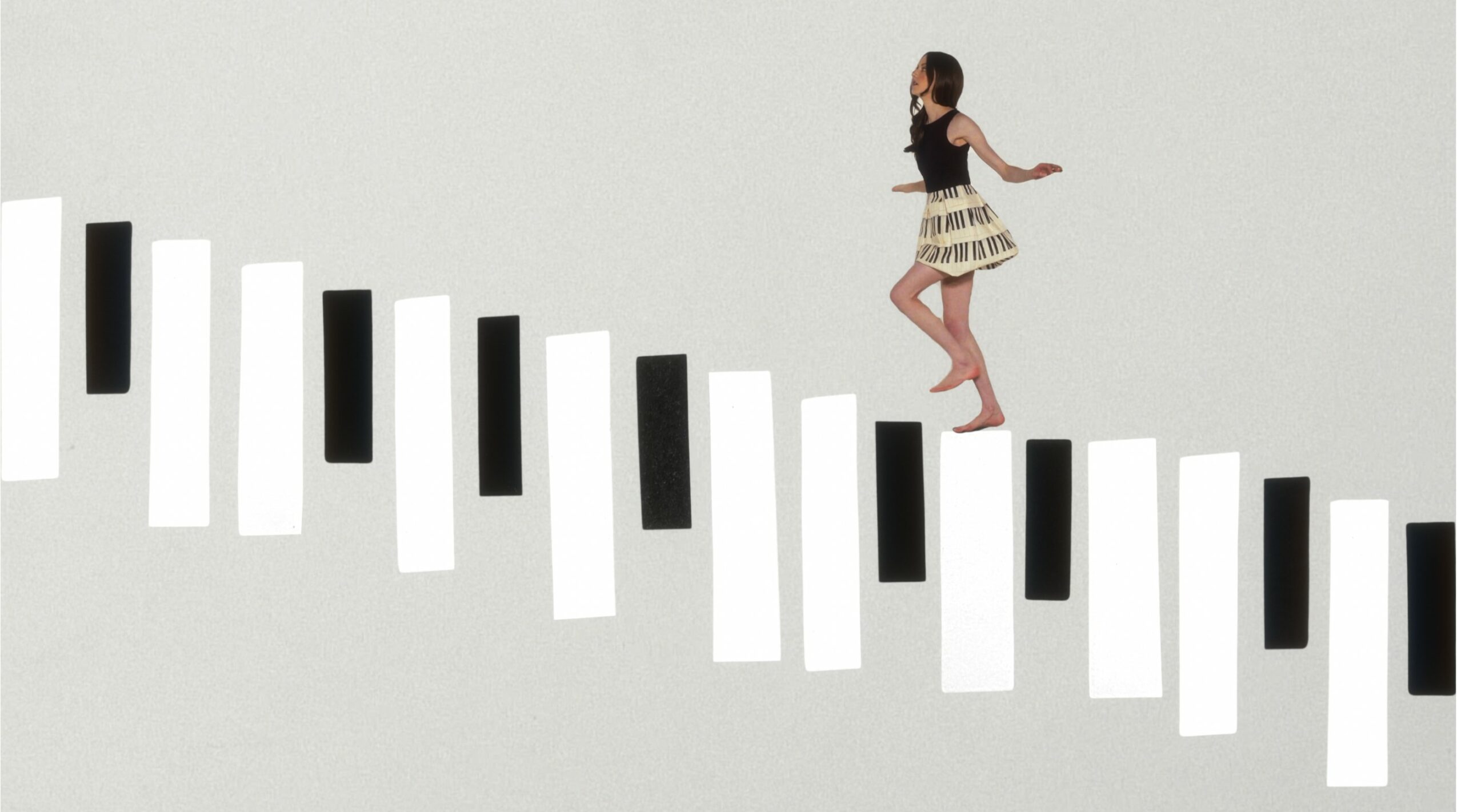 Young girl jumping over piano keys arranged diagonally on a plain background.