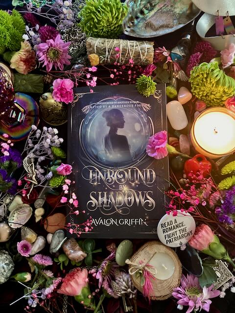 Book titled 'Unbound Shadows' by Avalon Griffin surrounded by flowers, candles, and decorative objects.