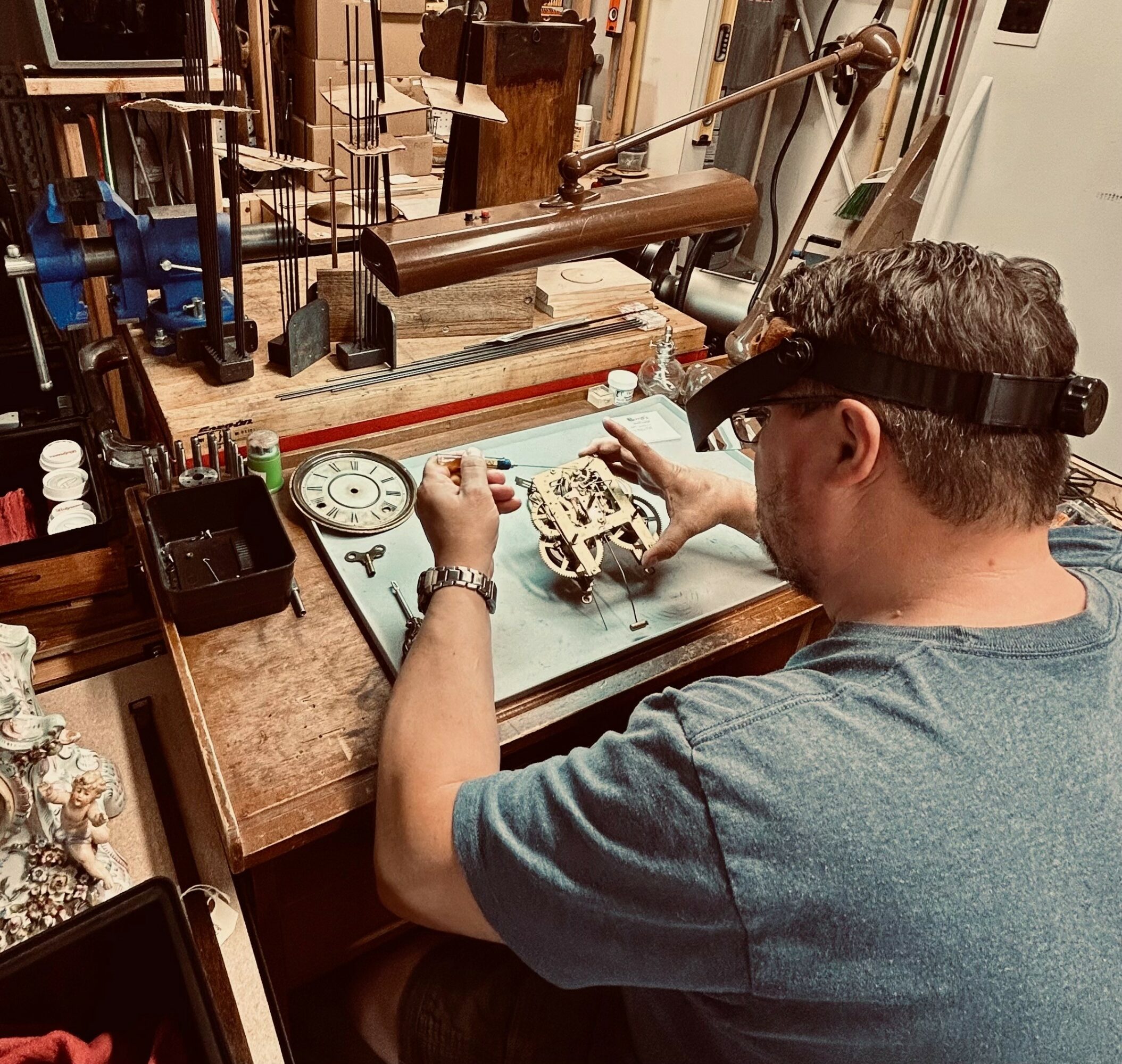 Person working on a mechanical device at a workbench with tools and equipment around.
