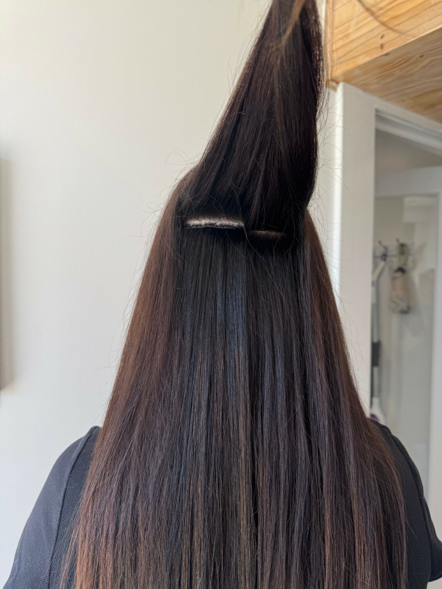 Long, straight, dark hair with a shiny appearance, hanging down against a white background.