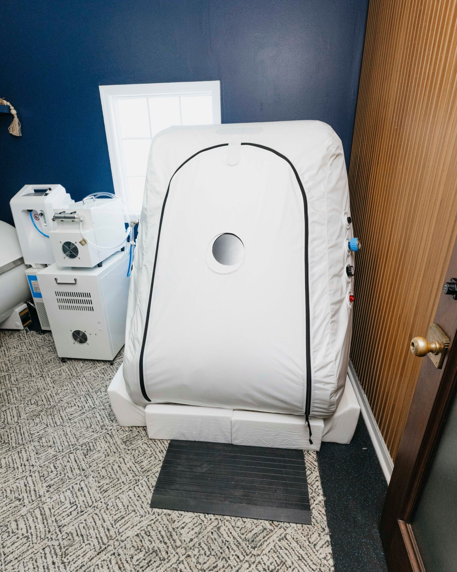 Medical imaging machine covered with a white cloth in a room with dark blue wall and wooden door.