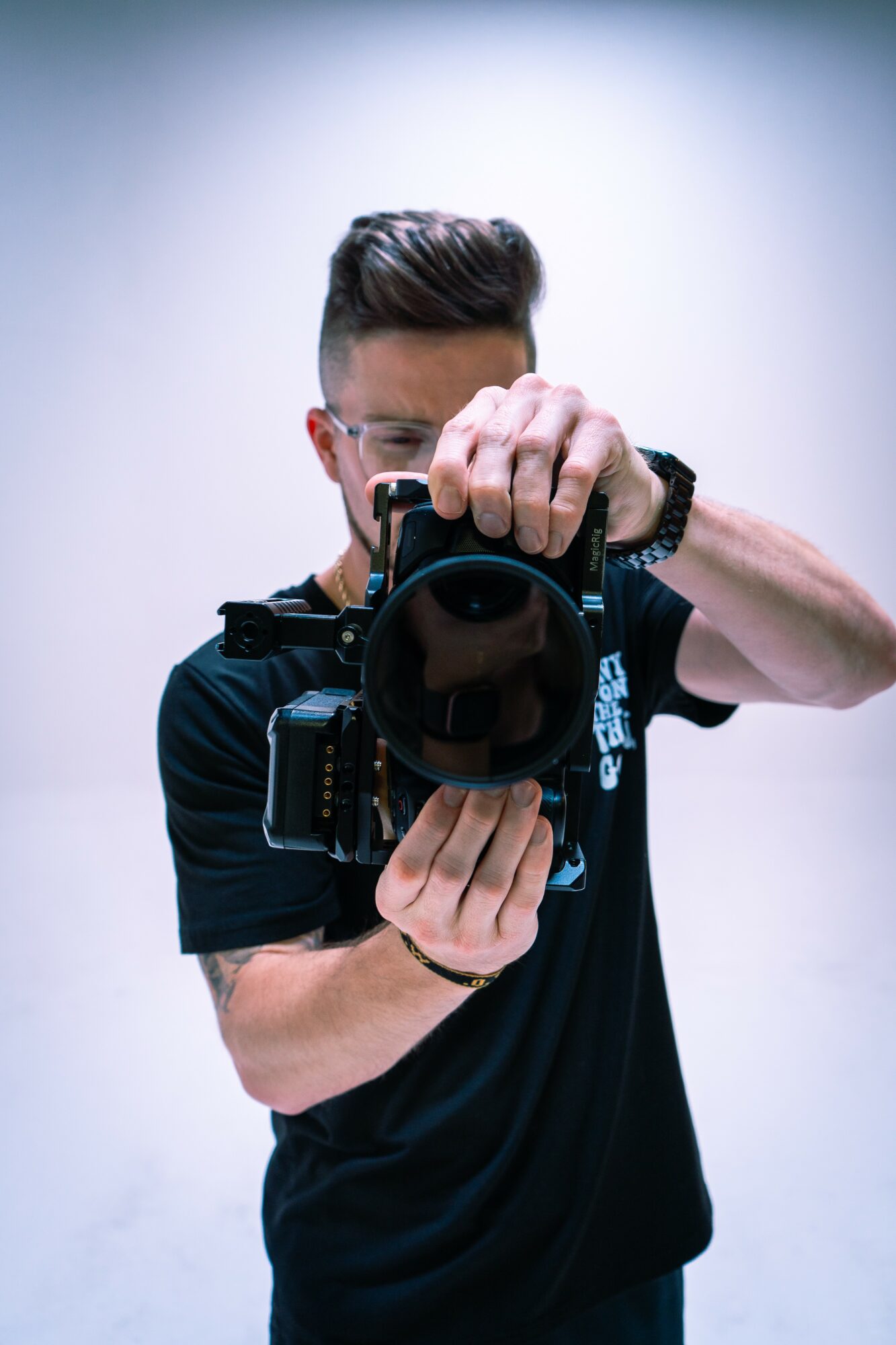 Person taking a photo with a camera, facing forward, with a plain background.