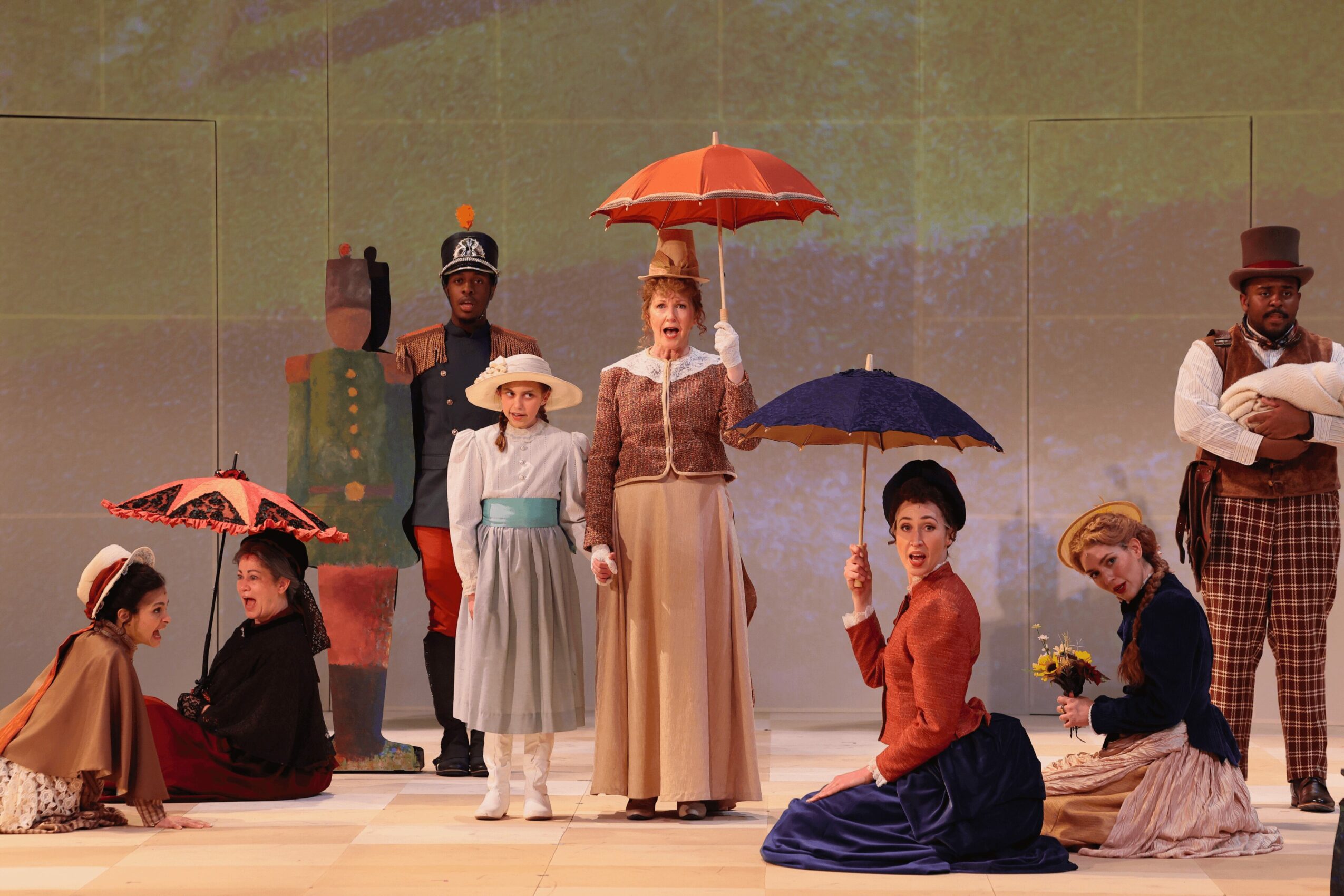 Group of people in vintage clothing with umbrellas, on stage, performing a scene, with a plain background.