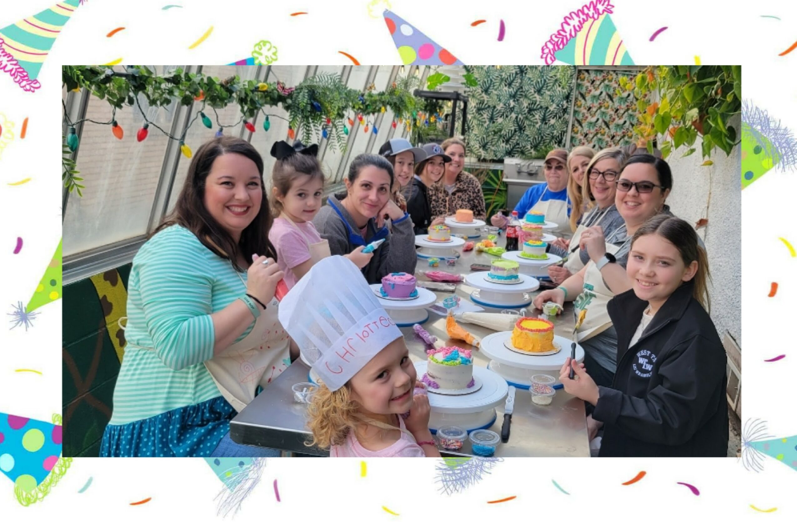 Group of children and adults celebrating at a decorated outdoor party table with cakes and plates.