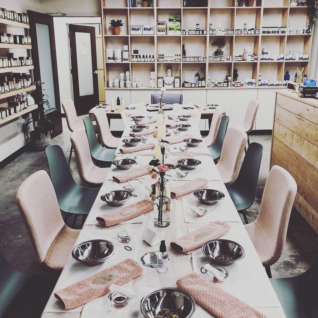 Long dining table with chairs, set with bowls, napkins, and utensils in a room with shelves and a door.