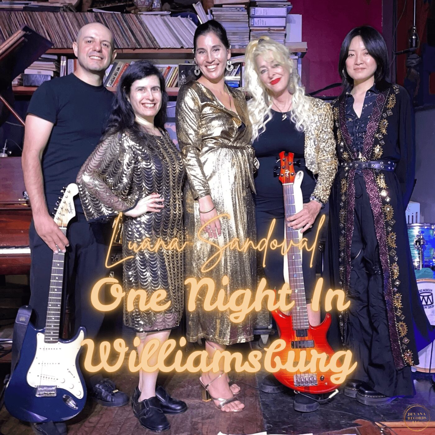 Five people standing together in a room with bookshelves, two holding guitars, smiling, with text overlay reading 'One Night In Williamsburg'.