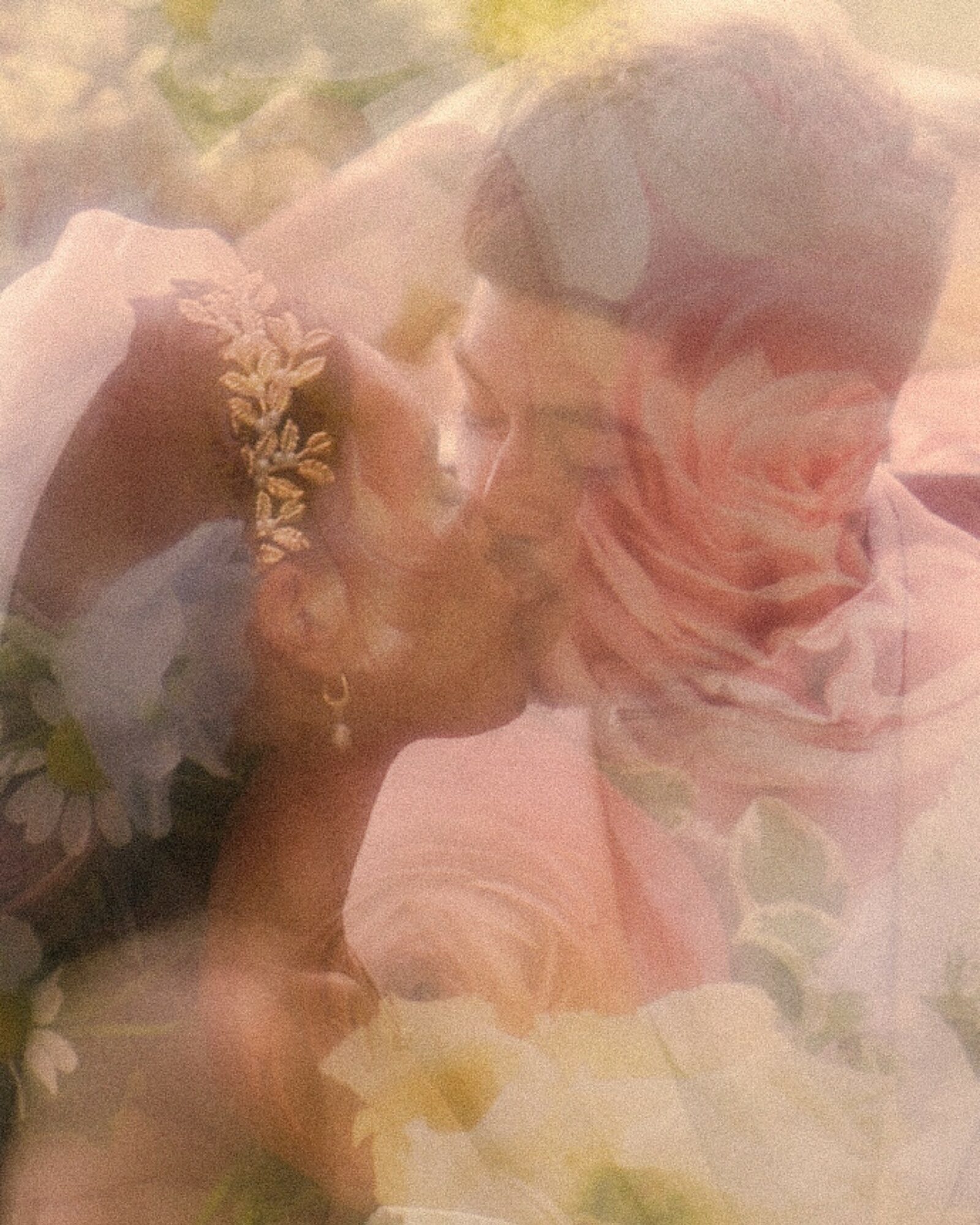 A couple appears to be kissing, with a soft focus and floral background, creating a dreamy, romantic scene.