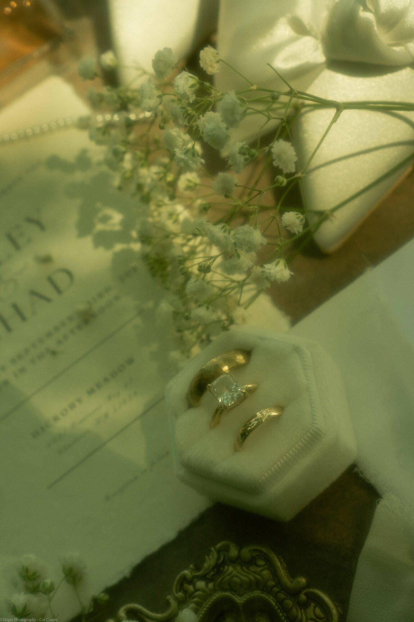Ring box with rings, flowers, and a document on a table, viewed from above.