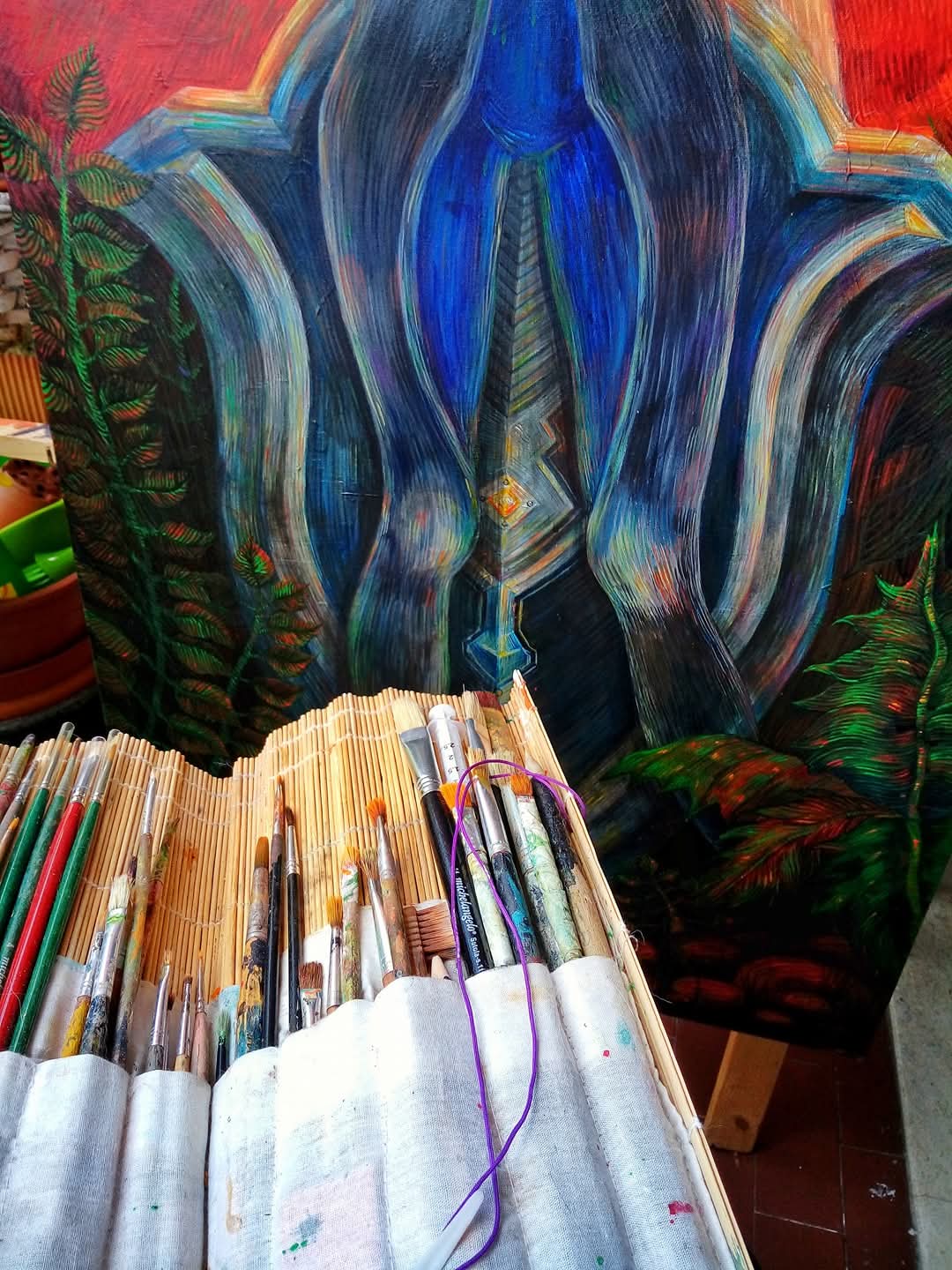 Colorful abstract painting with blue, green, and red hues, surrounded by art supplies including pens and markers.
