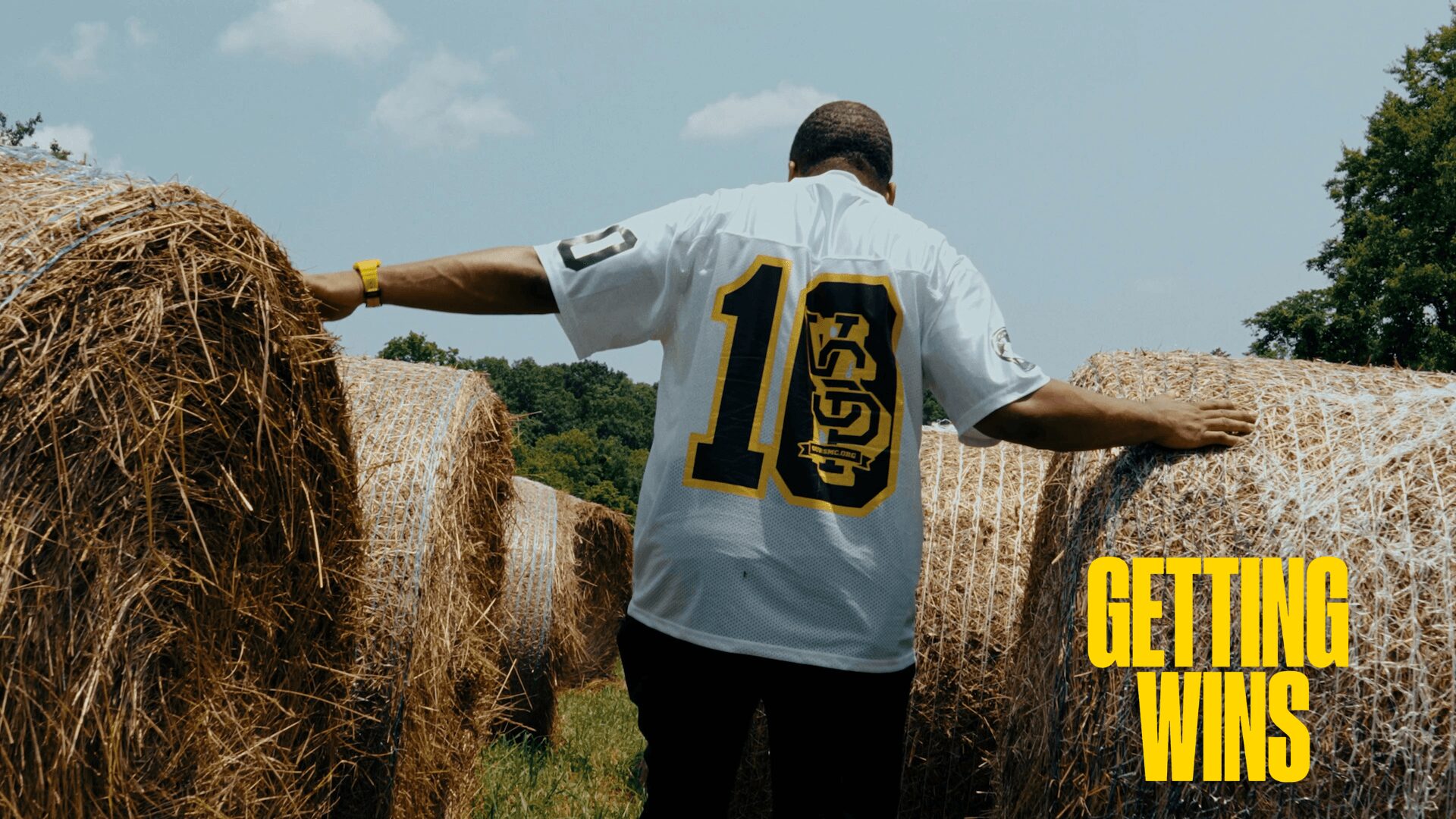 Person in a white jersey with the number 10 walking between hay bales outdoors, with yellow text reading 'Getting Wins'.