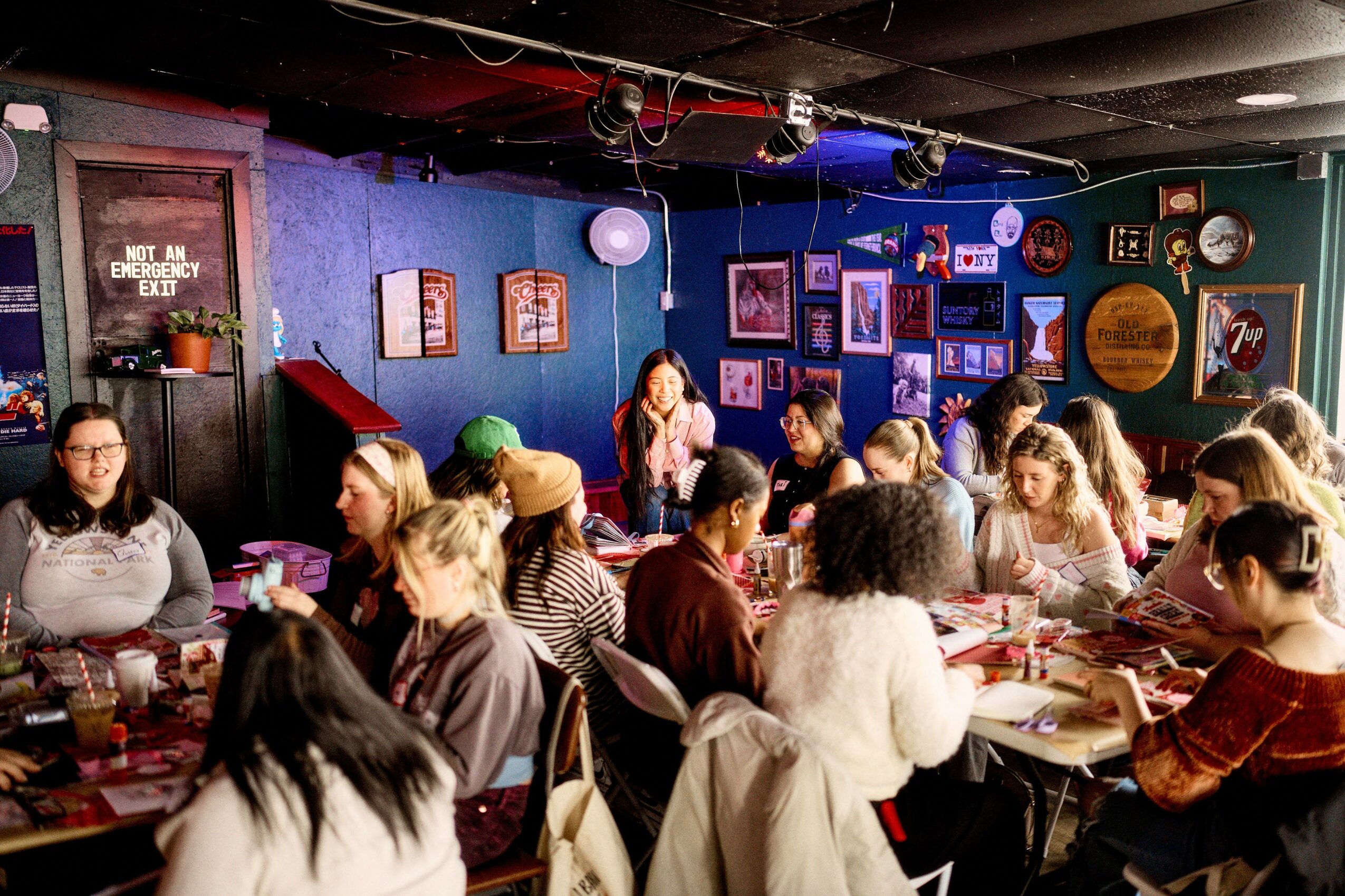 Group of people sitting at tables in a colorful room with framed pictures and decorations on the walls.