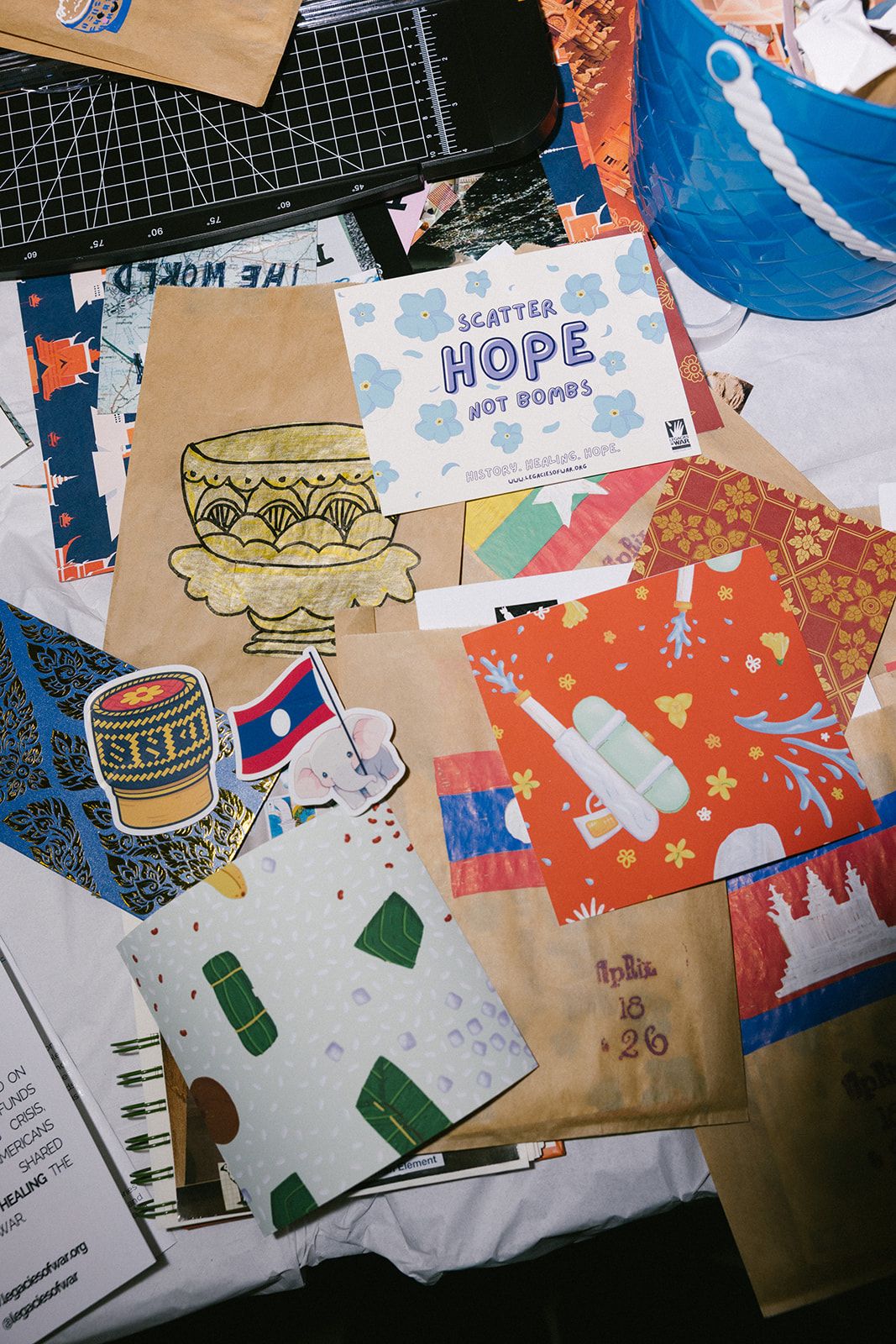 Collection of colorful cards, stickers, and paper crafts on a table, including a Hope card, a cupcake sticker, and patterned papers.