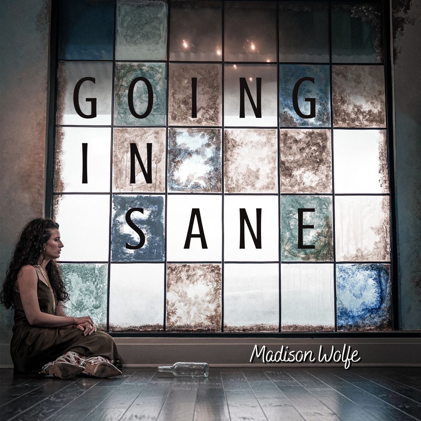 Person sitting on floor in front of large window with the words 'GOING IN SANE' displayed, and 'Madison Wolfe' signature.