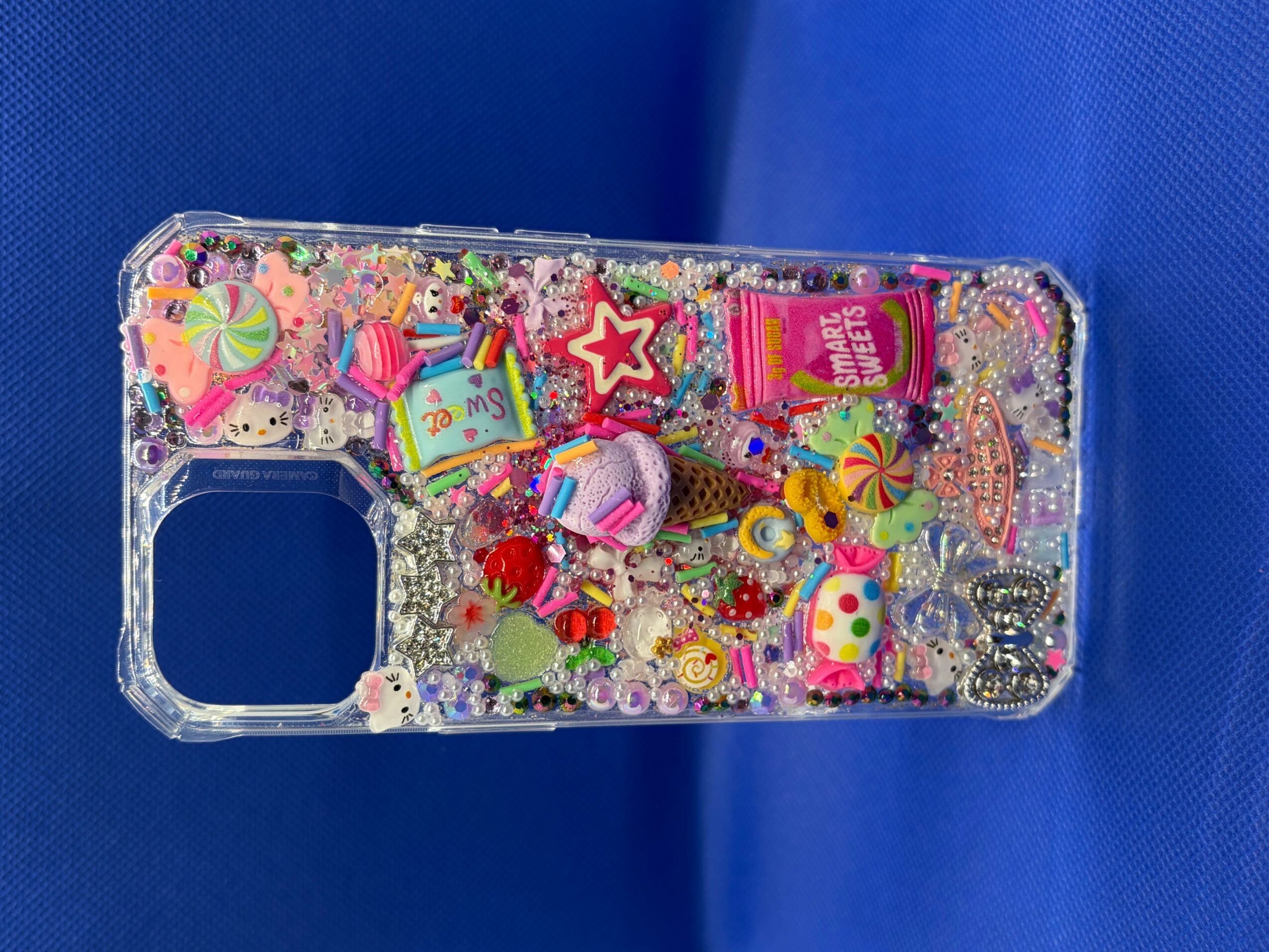 Clear phone case filled with colorful small toys, beads, and decorations, on a blue background.