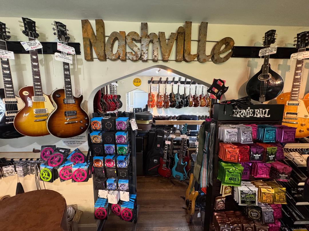Music store with guitars, accessories, and a sign reading Nashville, viewed from the front entrance.