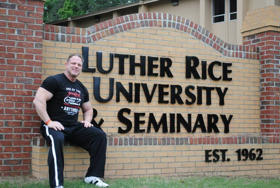 Person sitting on a bench in front of a sign for Luther Rice University and Seminary, established in 1962.
