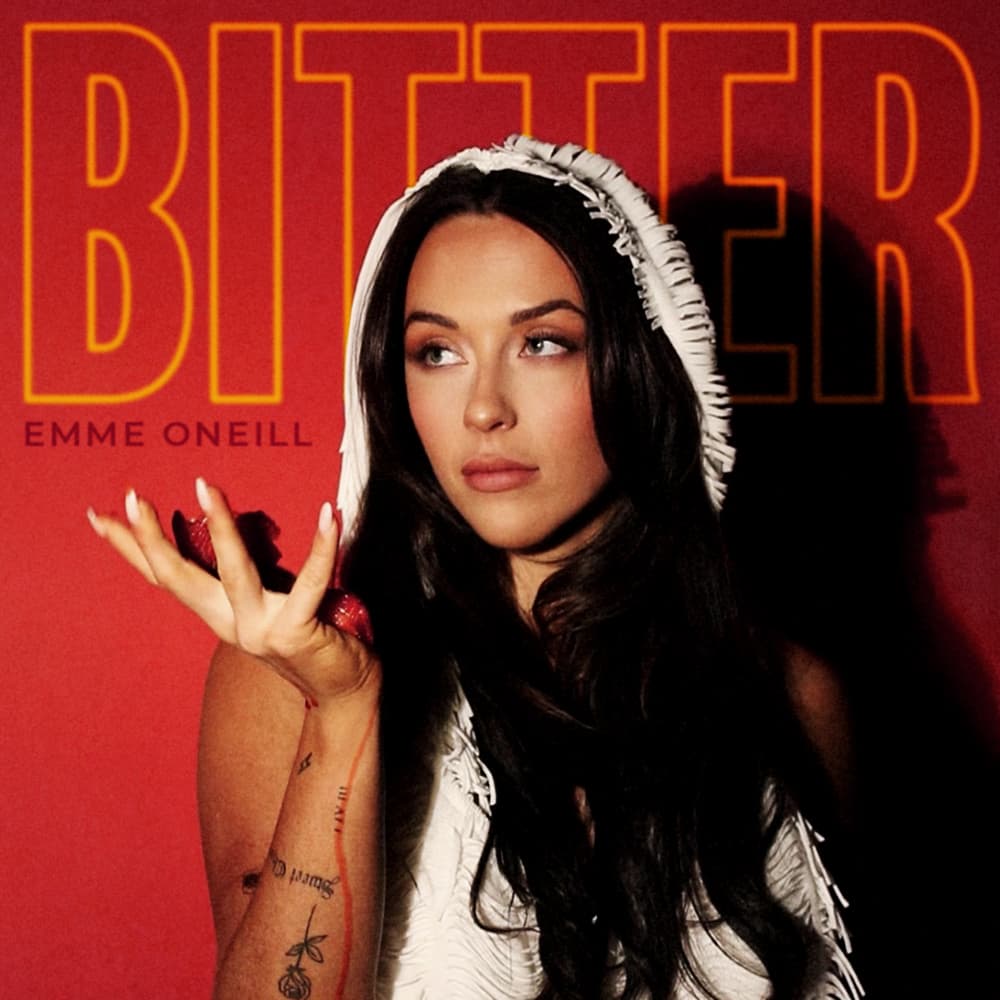 Woman with long dark hair wearing a hood, holding her hand up, against a red background with the word 'BITTER' in large letters.