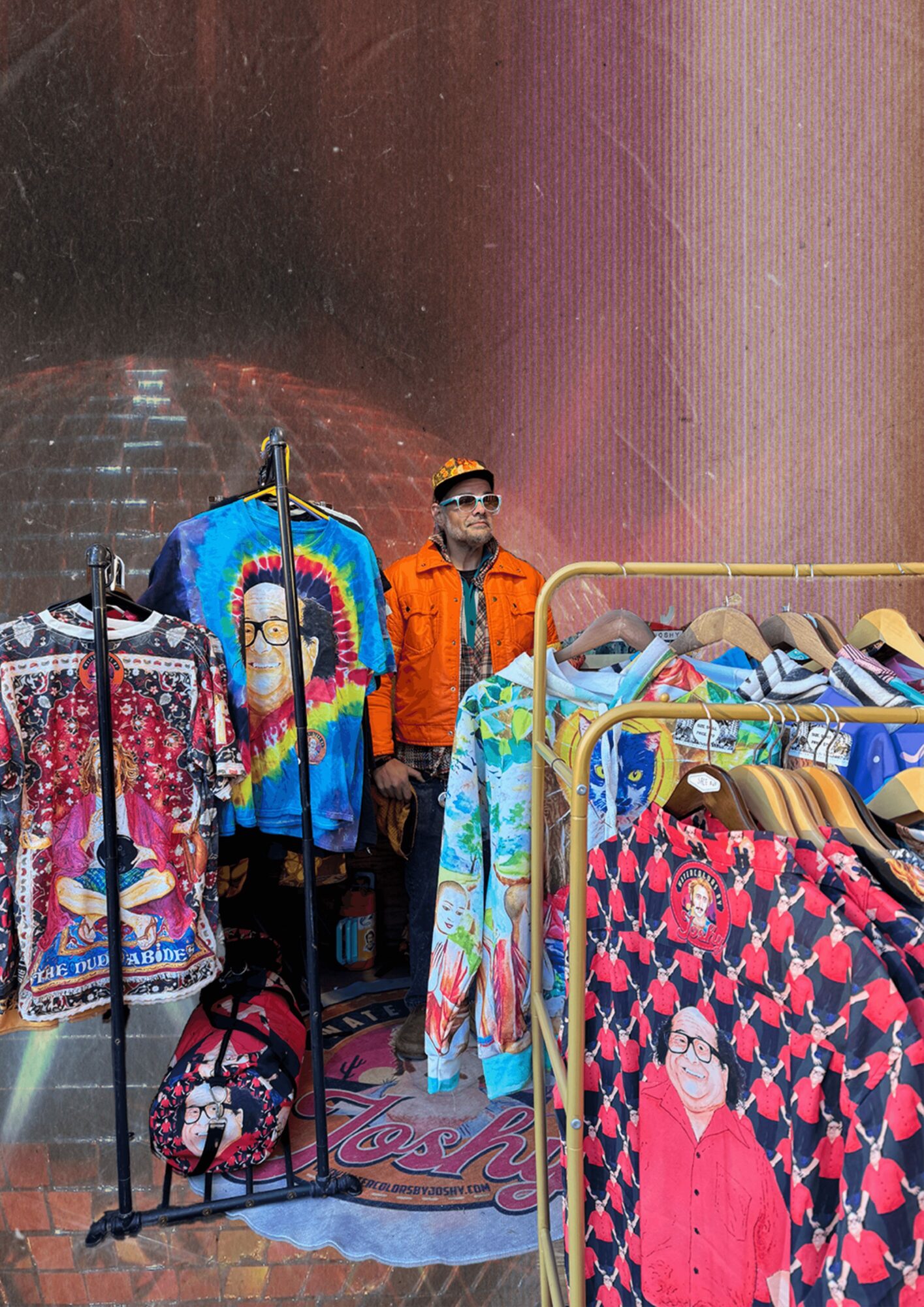 Clothing display with colorful garments and a person wearing sunglasses and an orange jacket, standing behind the display.