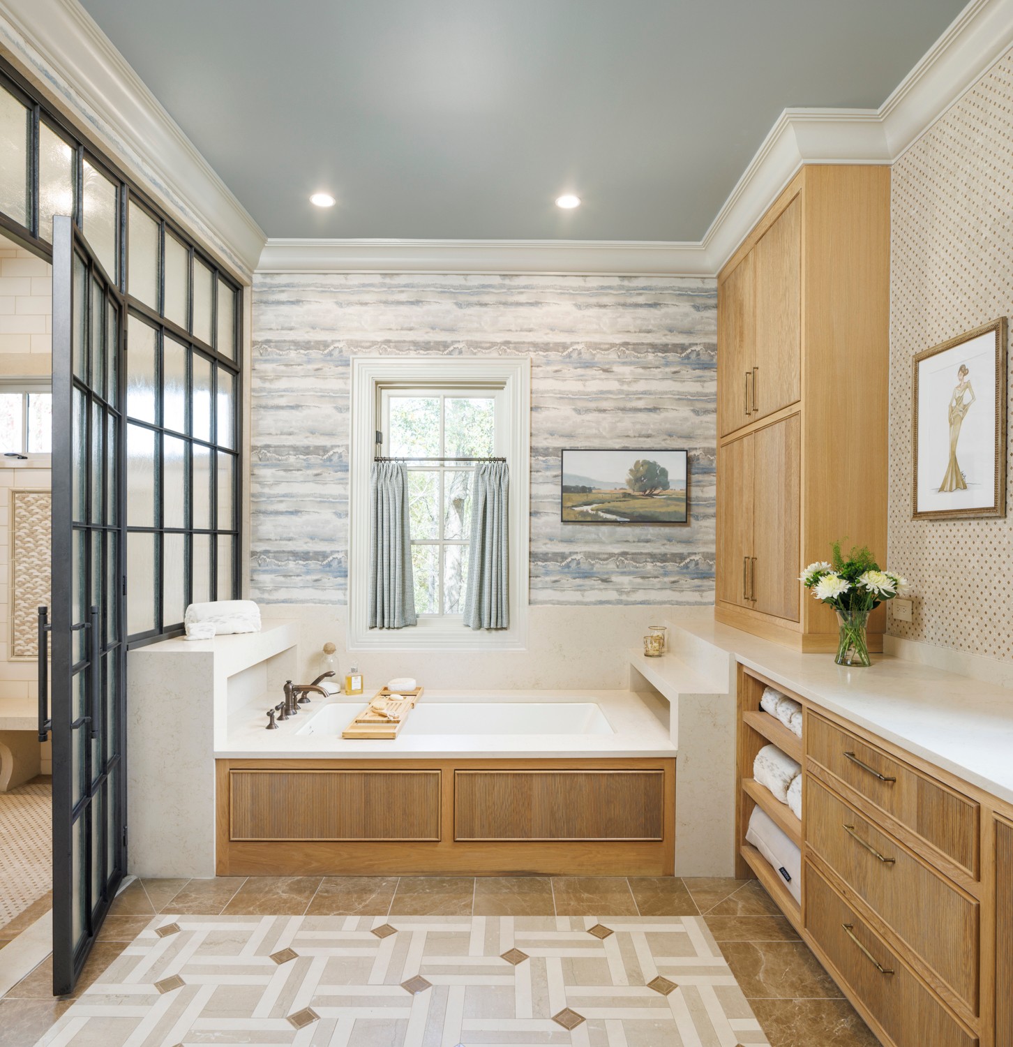 Bathroom with bathtub, wooden cabinets, a window with curtains, and a vase with flowers on the counter.
