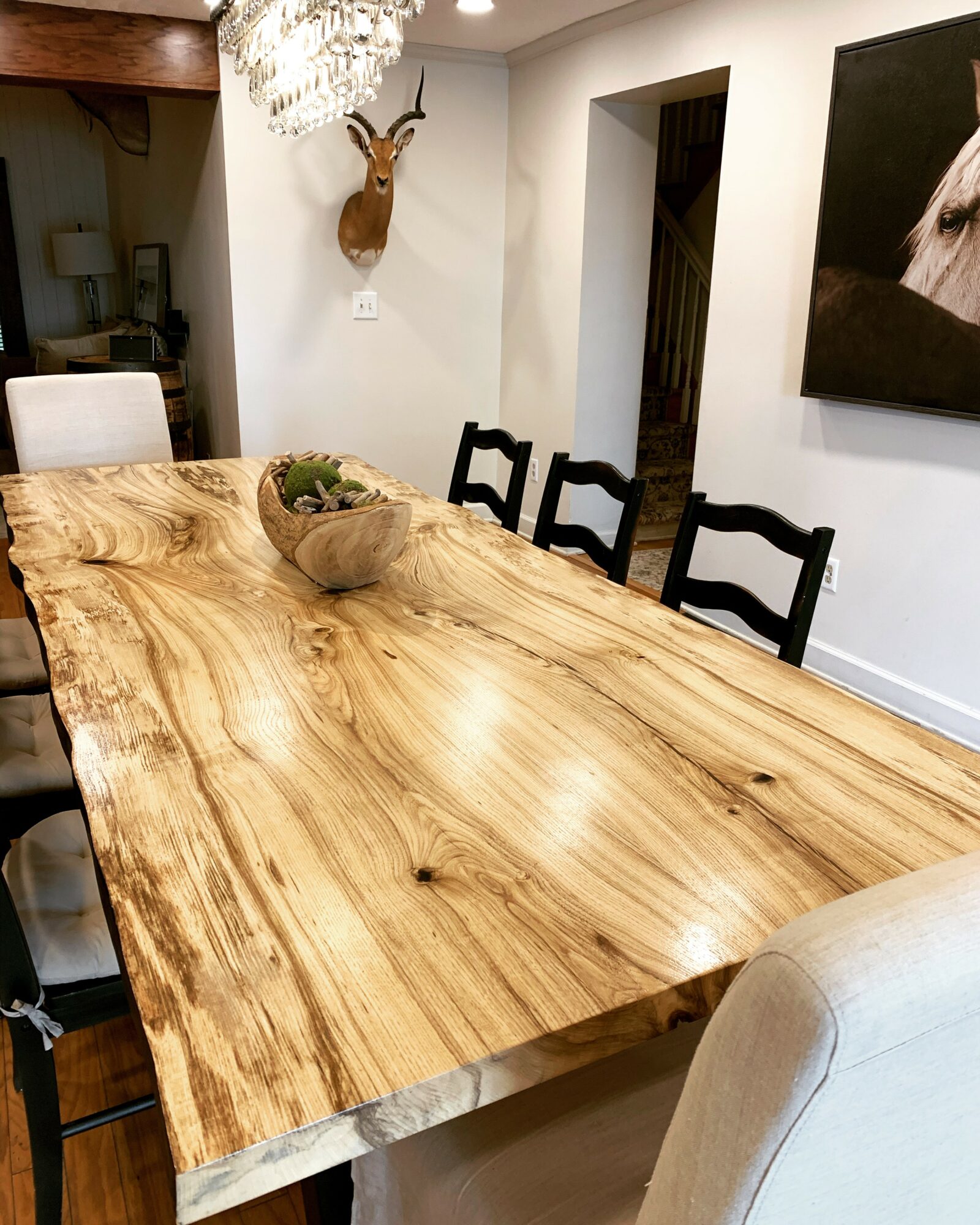 Wooden dining table with chairs, a decorative bowl, and wall art in a modern dining room.