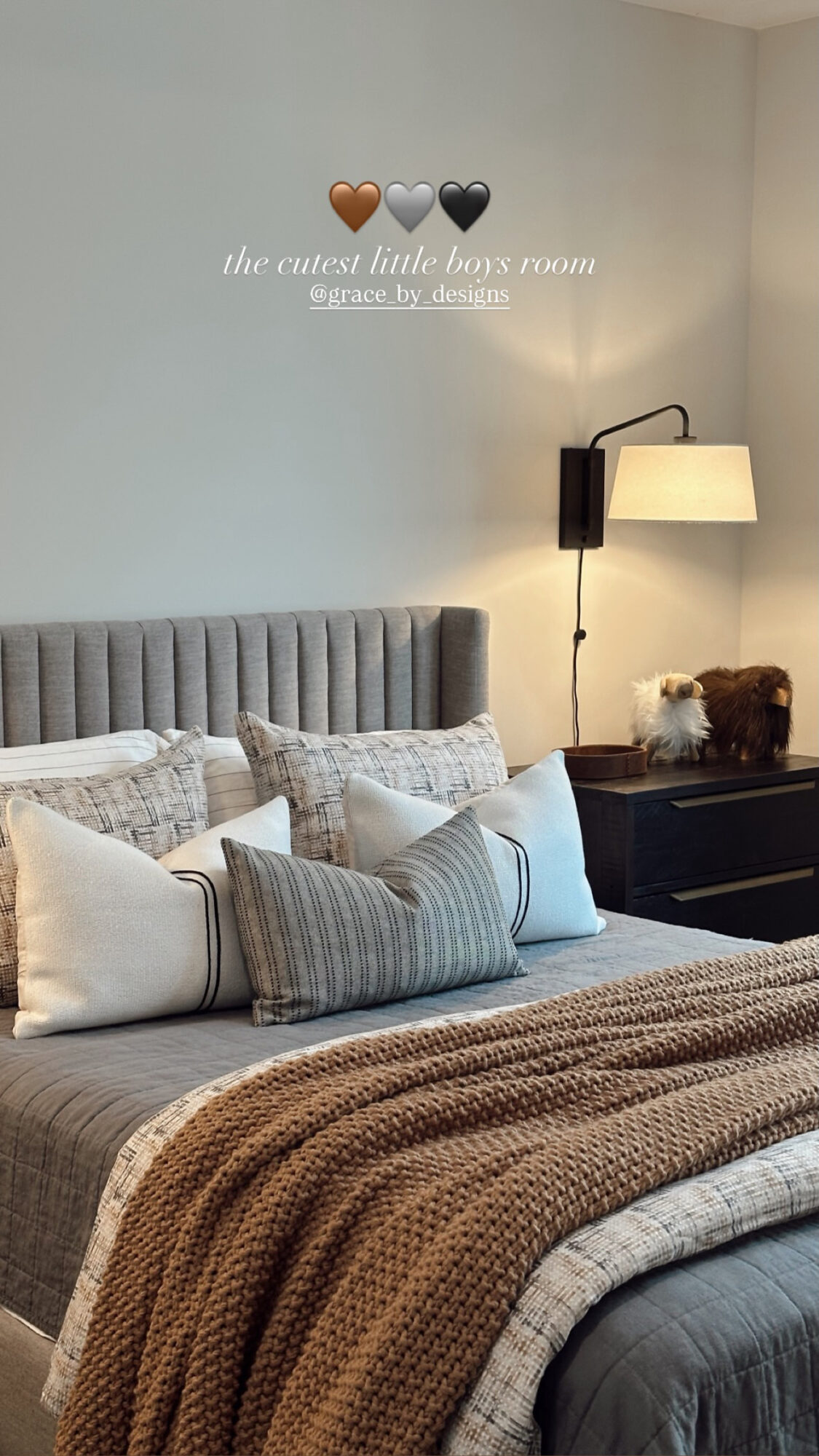 Bedroom with bed, pillows, wall decor, and a wall-mounted lamp, featuring a neutral color palette and cozy decor.
