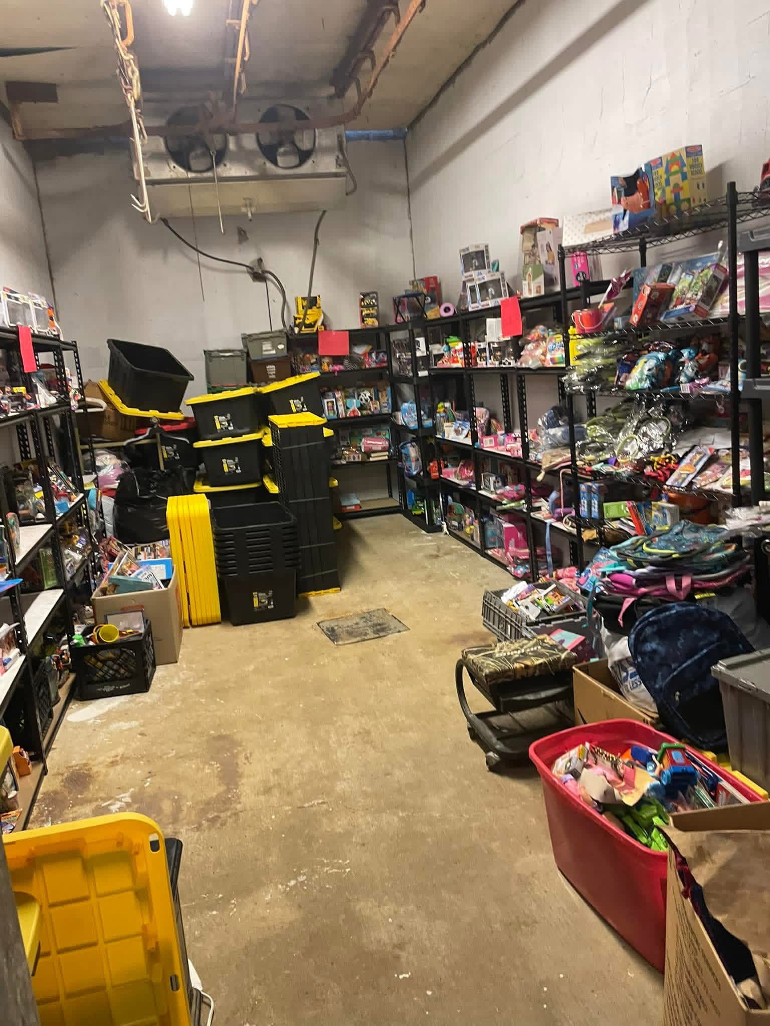 Shelves filled with toys and games in a storage room, with a yellow storage bin in the foreground.