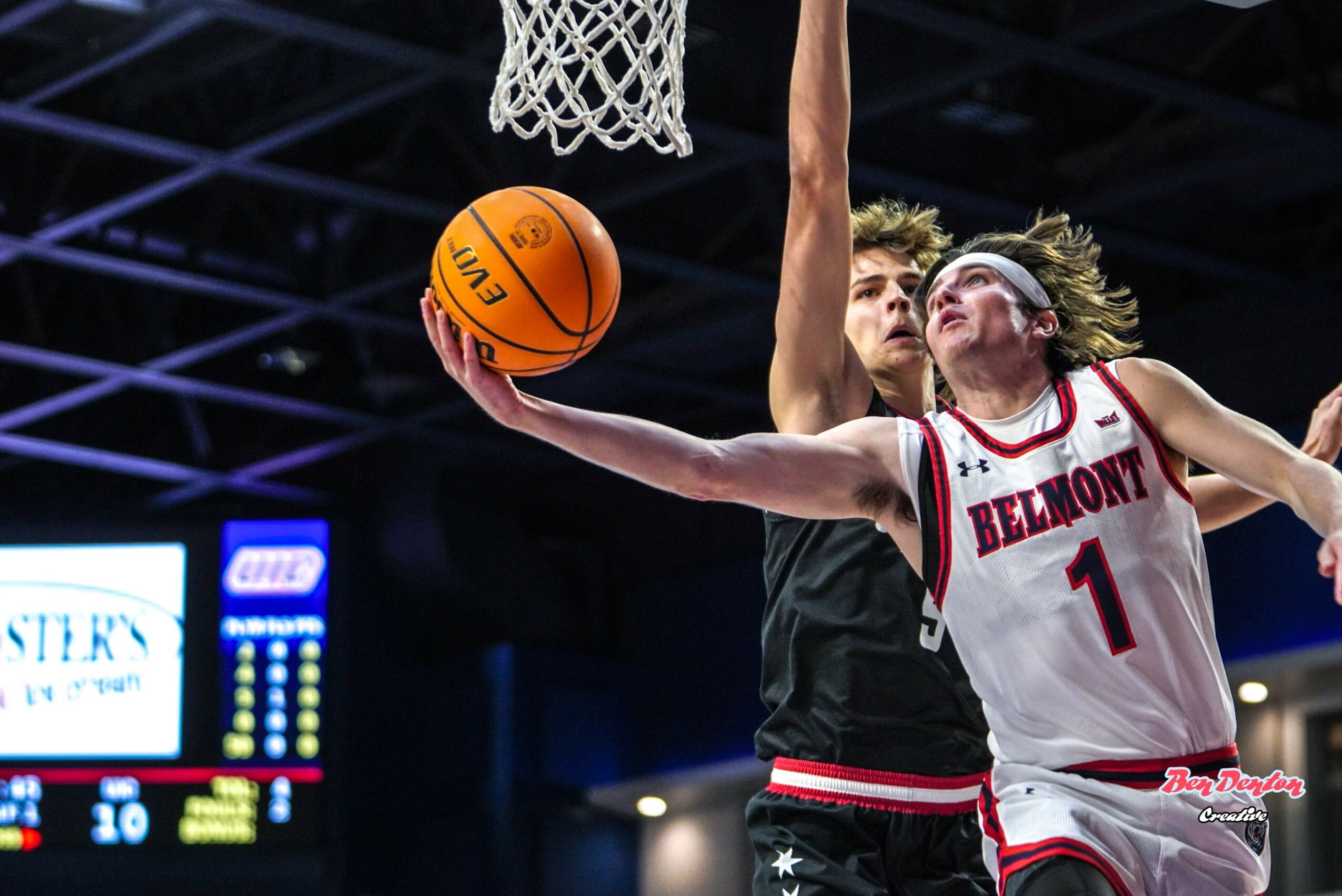 Two female basketball players compete near the hoop, one reaching for the ball, wearing Belmont jersey number 1.