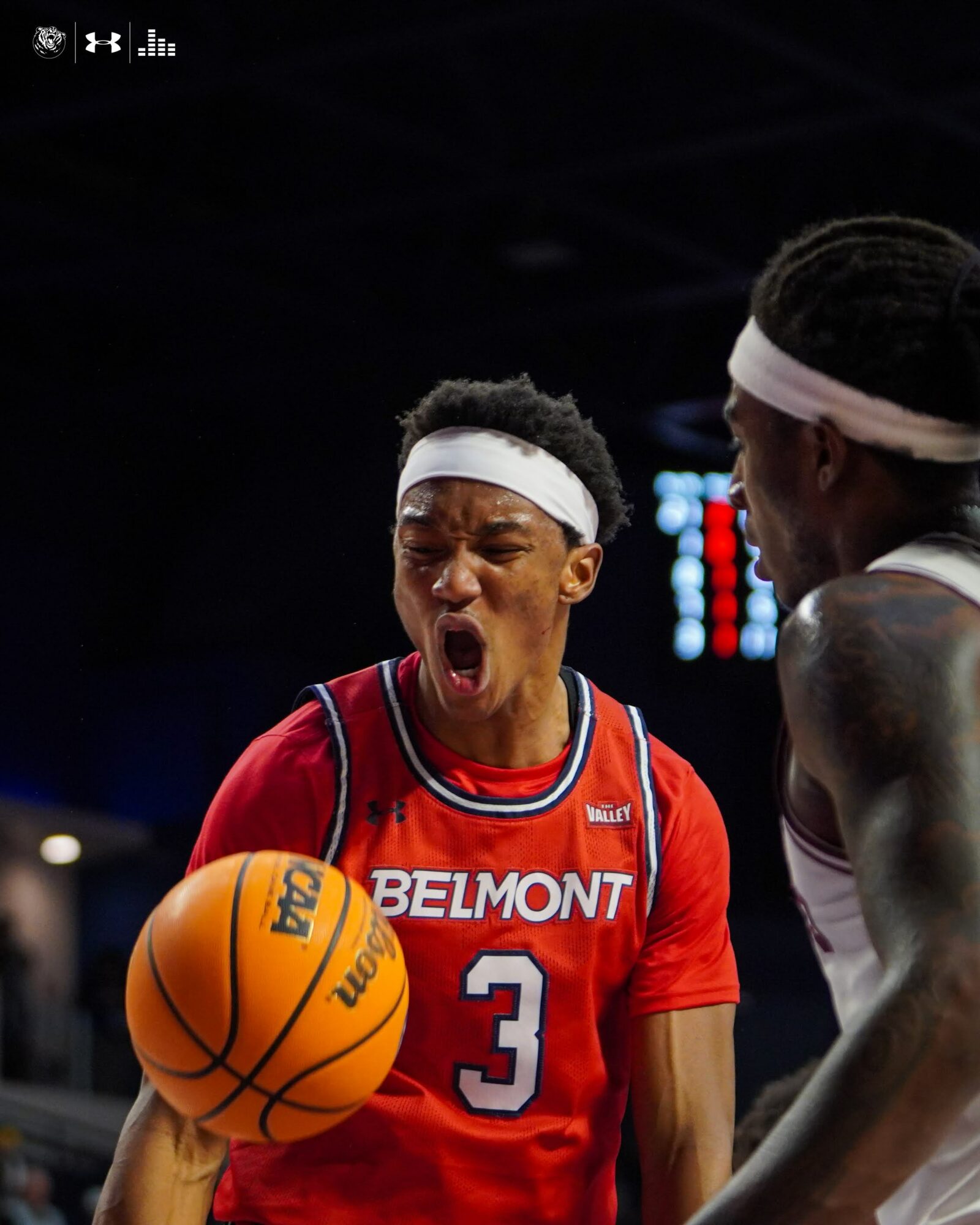Young basketball player in red jersey with number 3, shouting, holding a basketball, with another player nearby.