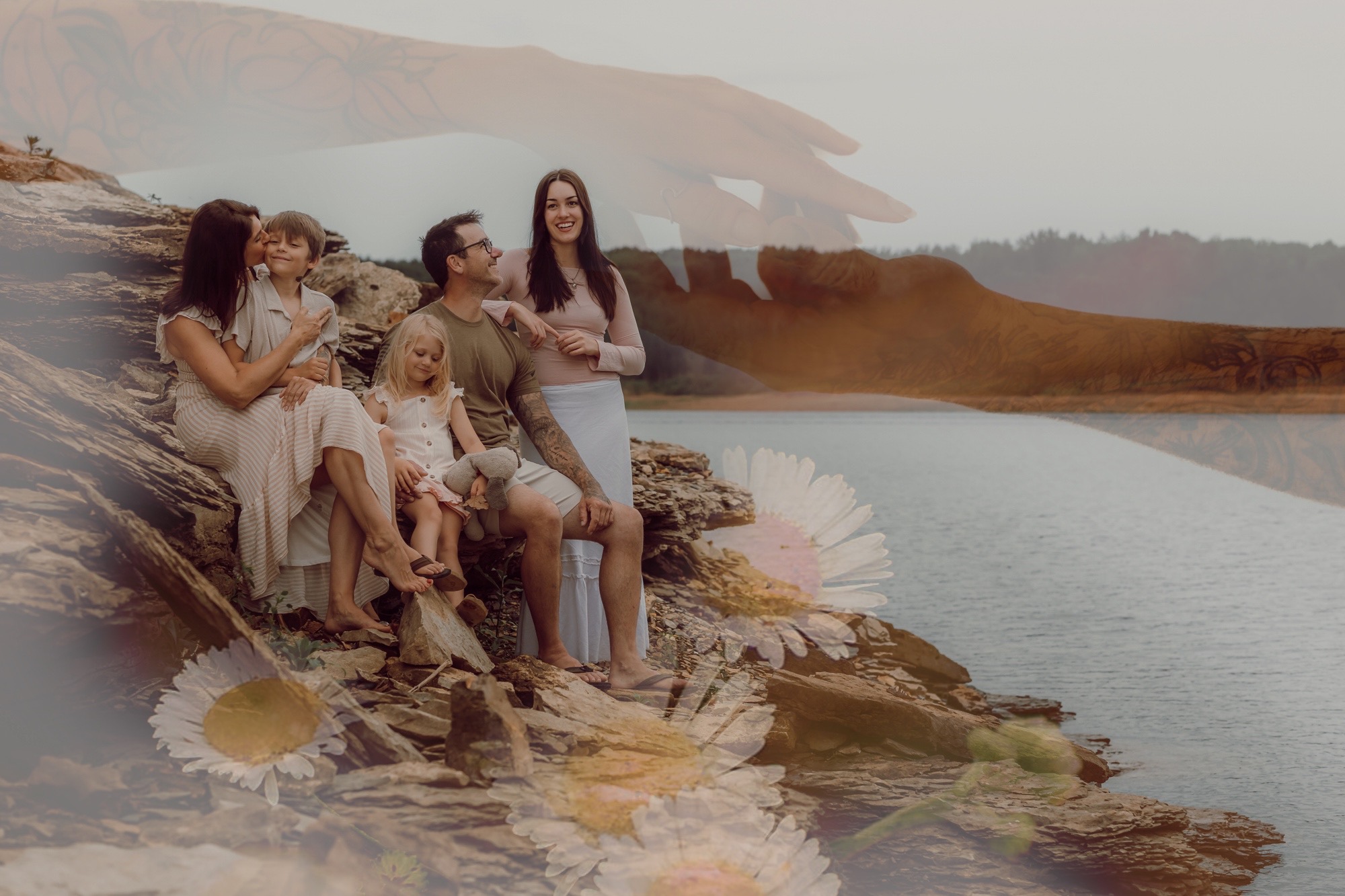 Group of people sitting on rocks by a body of water, with a landscape in the background.