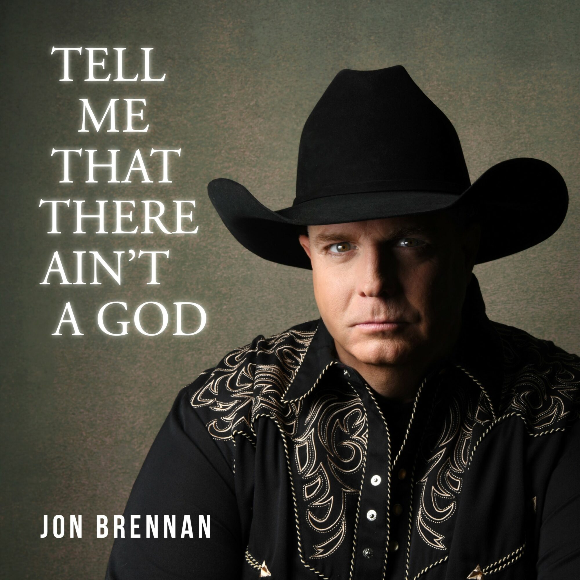 Man wearing a cowboy hat and black shirt with embroidery, looking serious, with text about God on the left side.