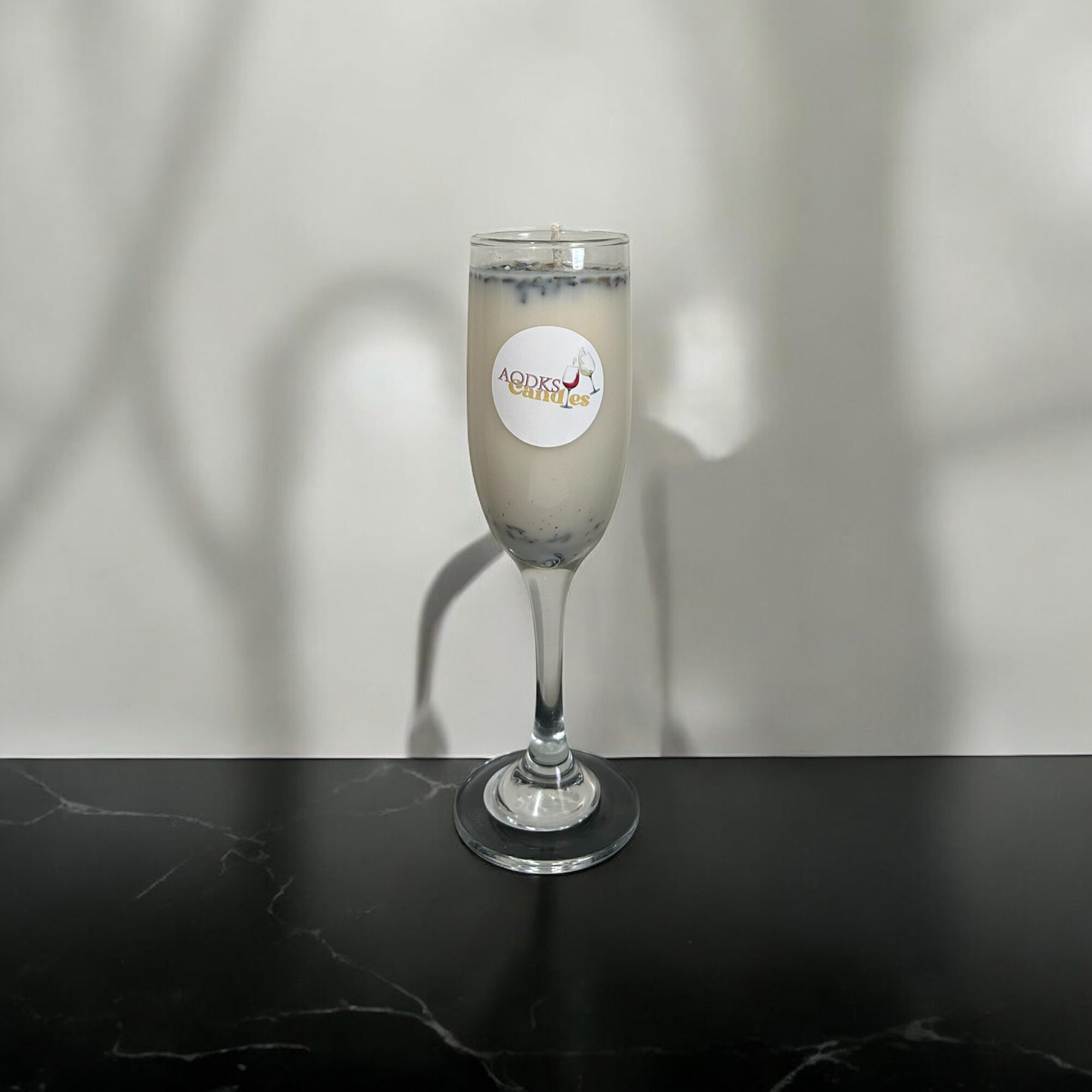 A glass of champagne with a logo on it, placed on a black surface against a light background.