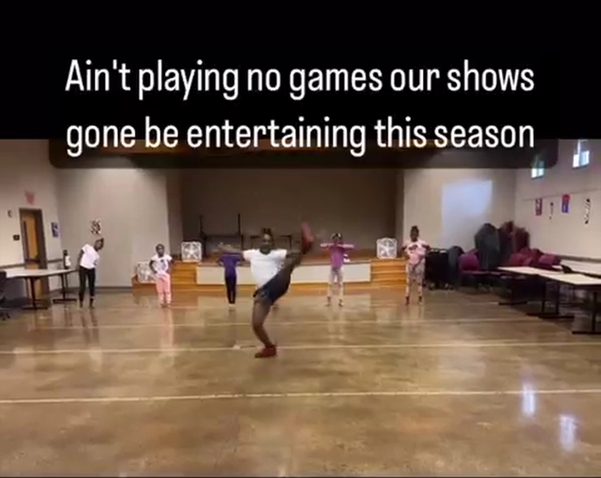 Group of children and an adult dancing in a gymnasium with wooden floors, walls, and some furniture, with text overlay.