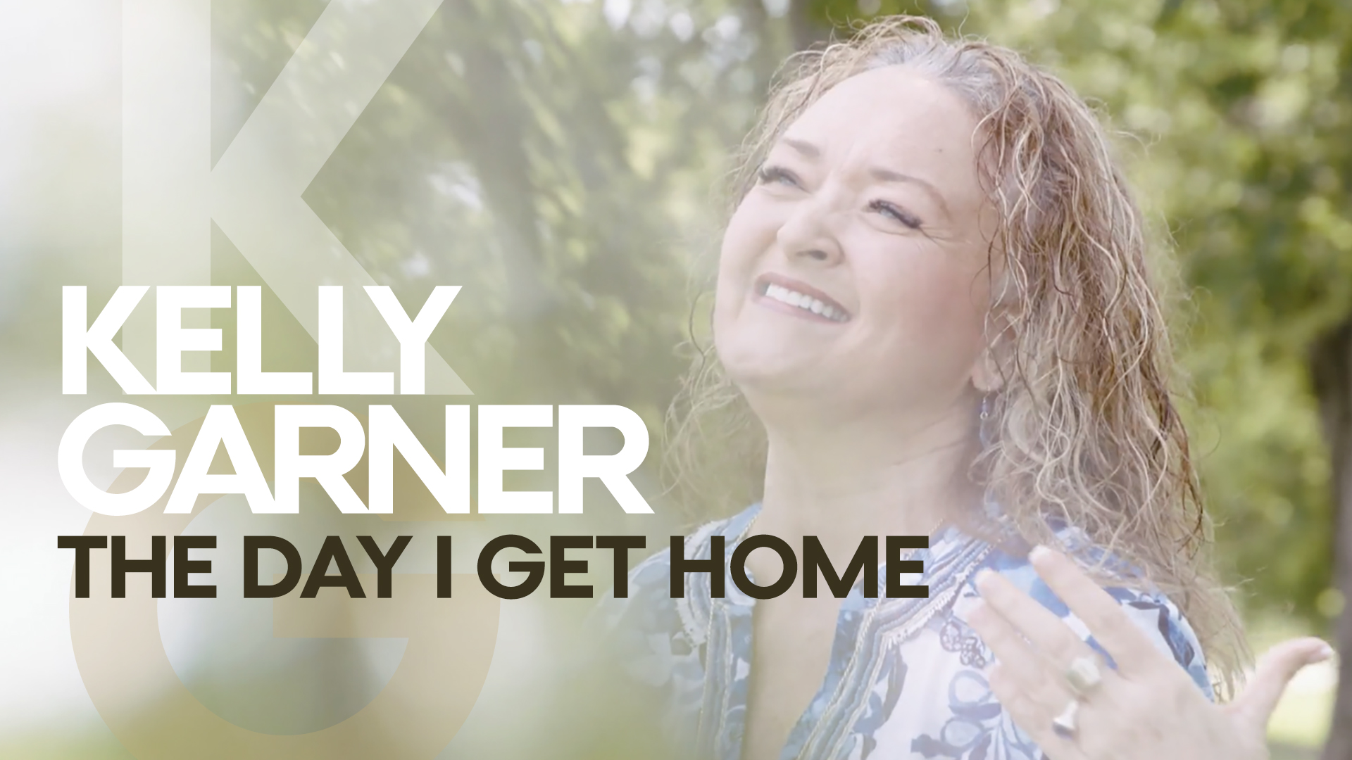 Woman smiling outdoors with trees in background, text overlay with artist and song title, bright and cheerful scene.