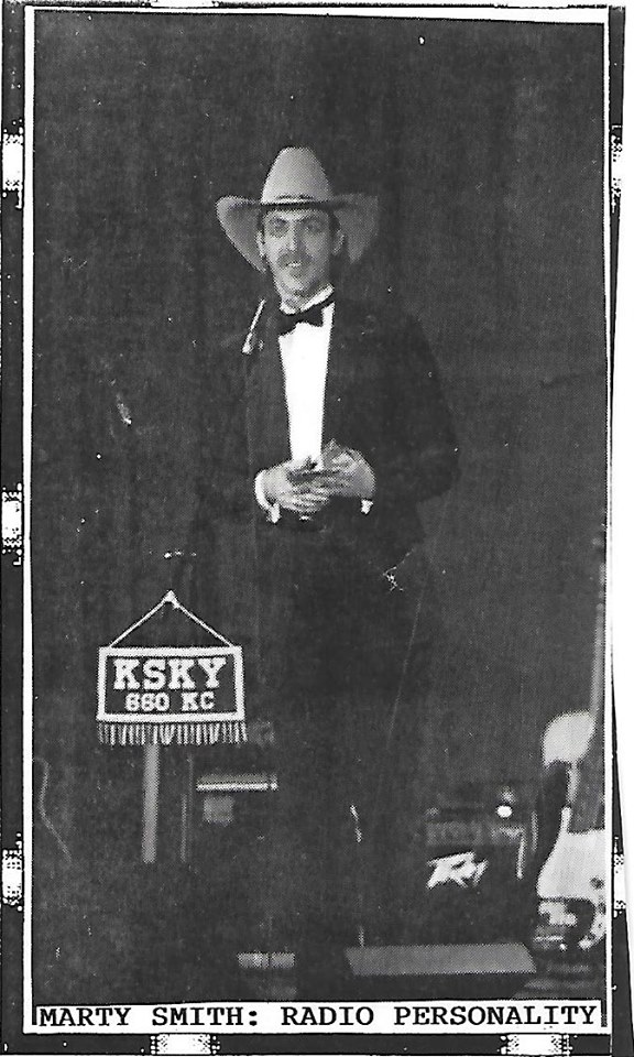 Man in a suit and hat holding a glass, standing next to a sign that reads 'KSKY 680 KC,' with a caption 'Marty Smith: Radio Personality.'
