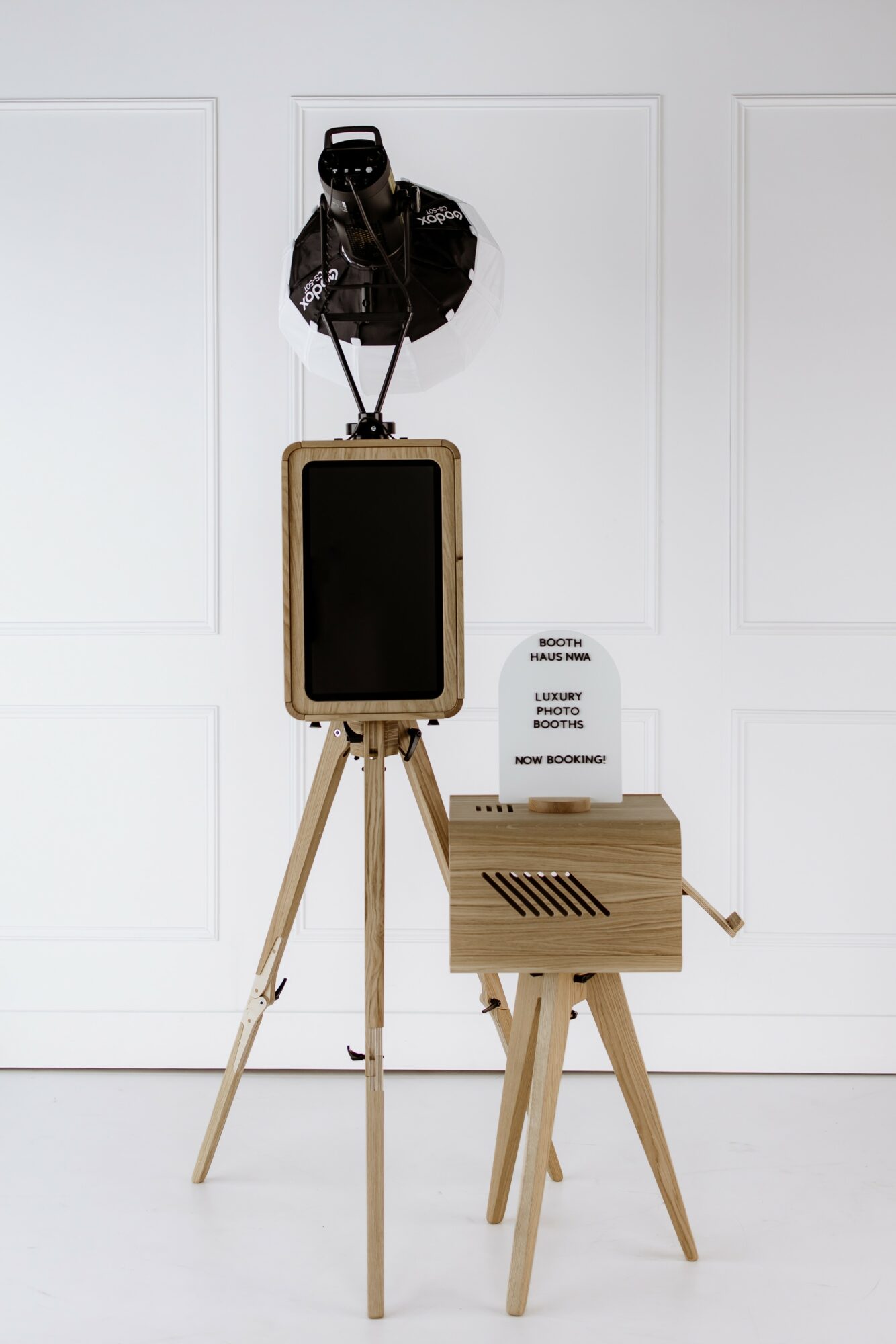 Lighting equipment and wooden stands with a blackboard, set against a white wall.