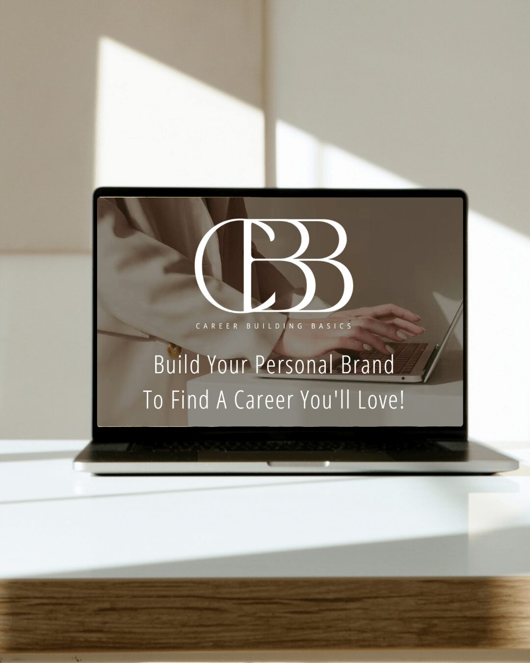 Laptop displaying a logo and text about building a personal brand on a white desk with sunlight and shadows.