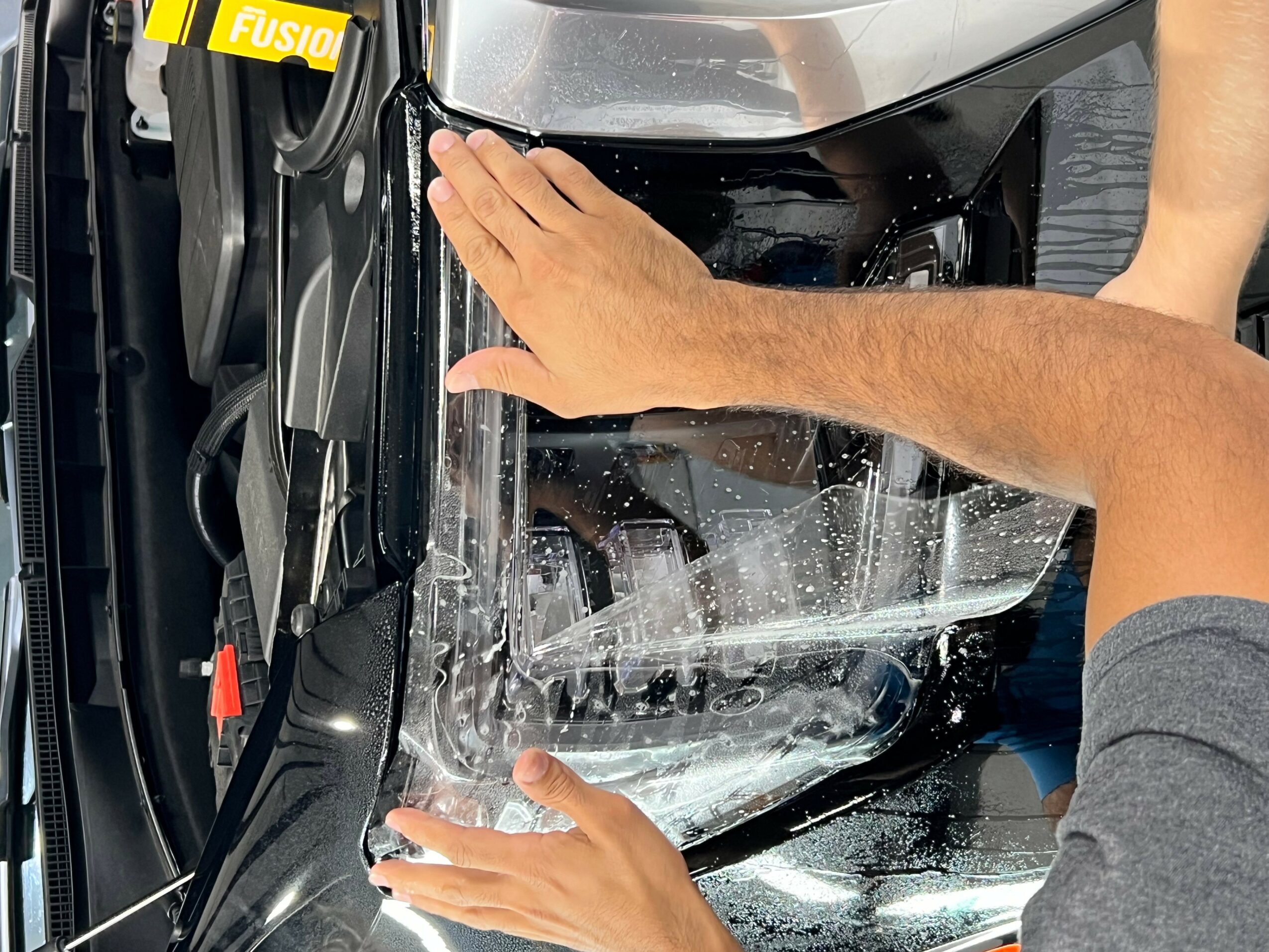 Person inspecting a car's front bumper with hands on the surface, showing a close-up view.