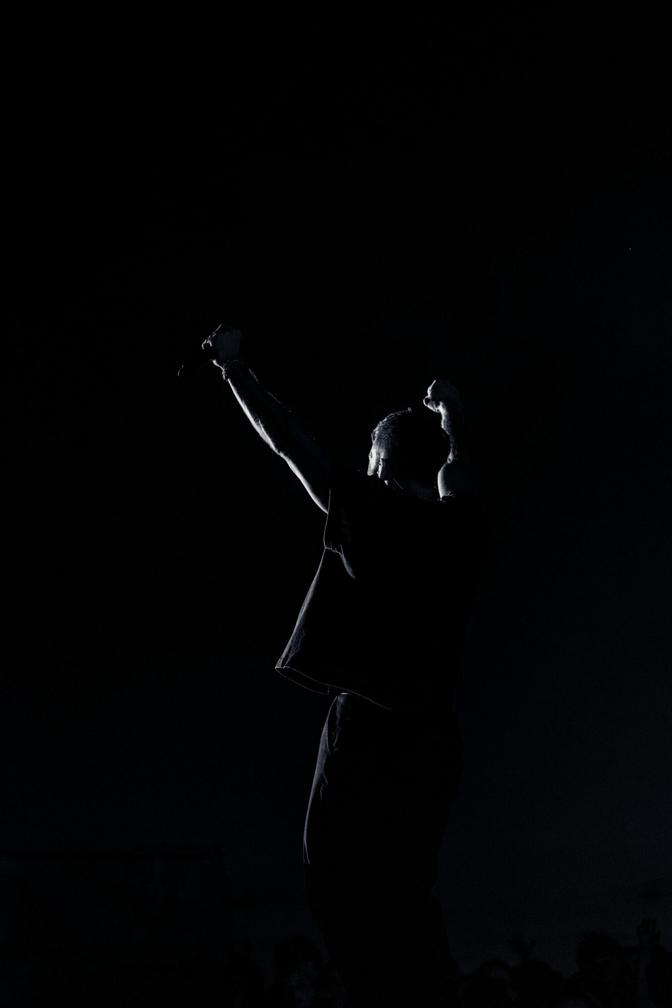 Person standing with one arm raised, silhouette visible against a dark background.