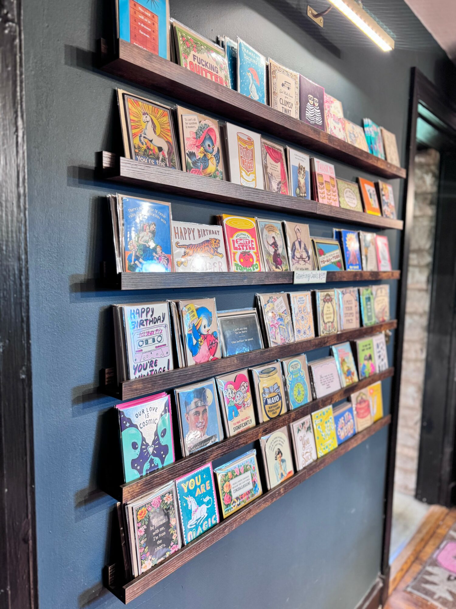 Bookshelves with colorful children's books mounted on a dark wall, arranged on five horizontal shelves.