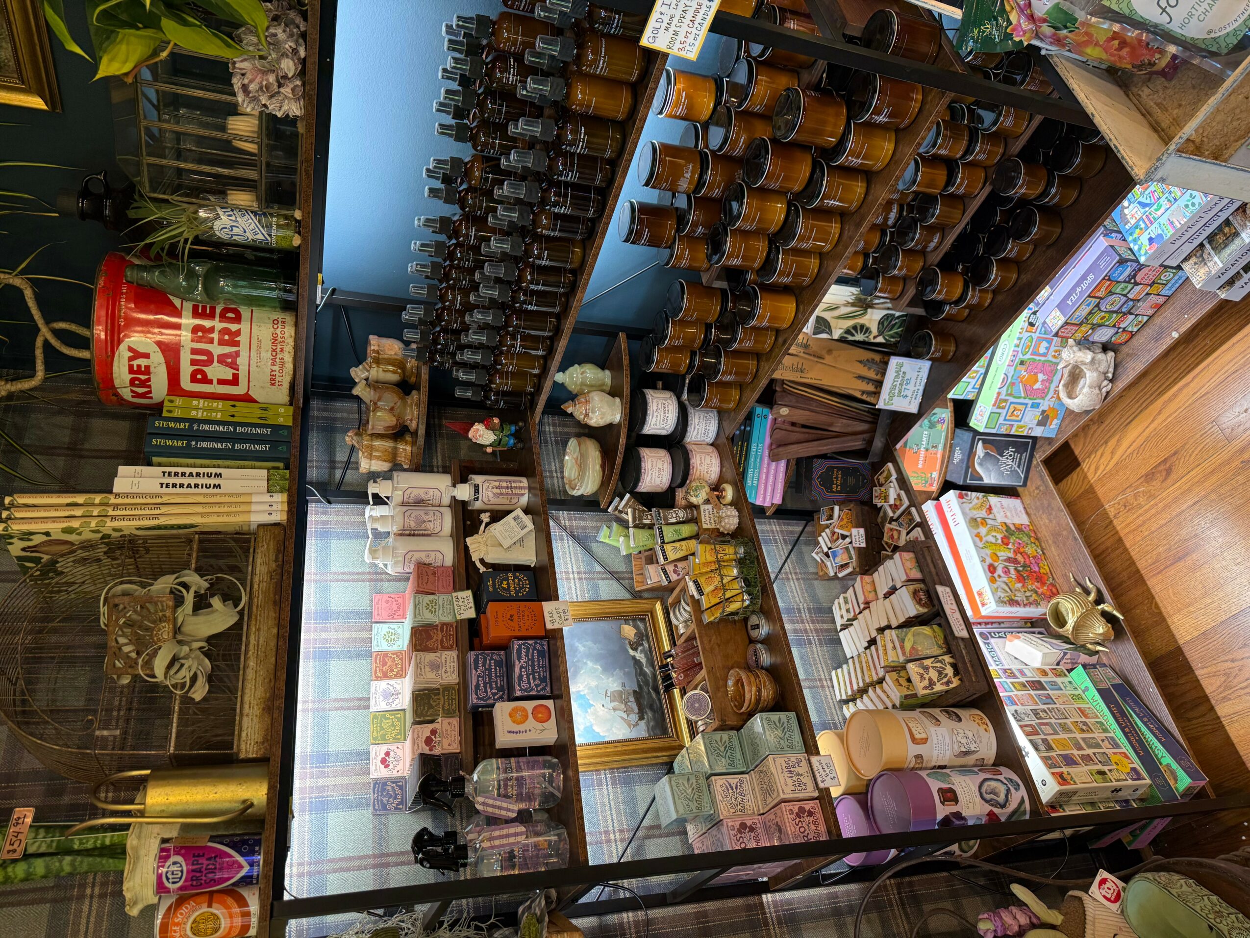 Display case with various jars, bottles, and boxes of products, shelves with small items, and a wooden floor.