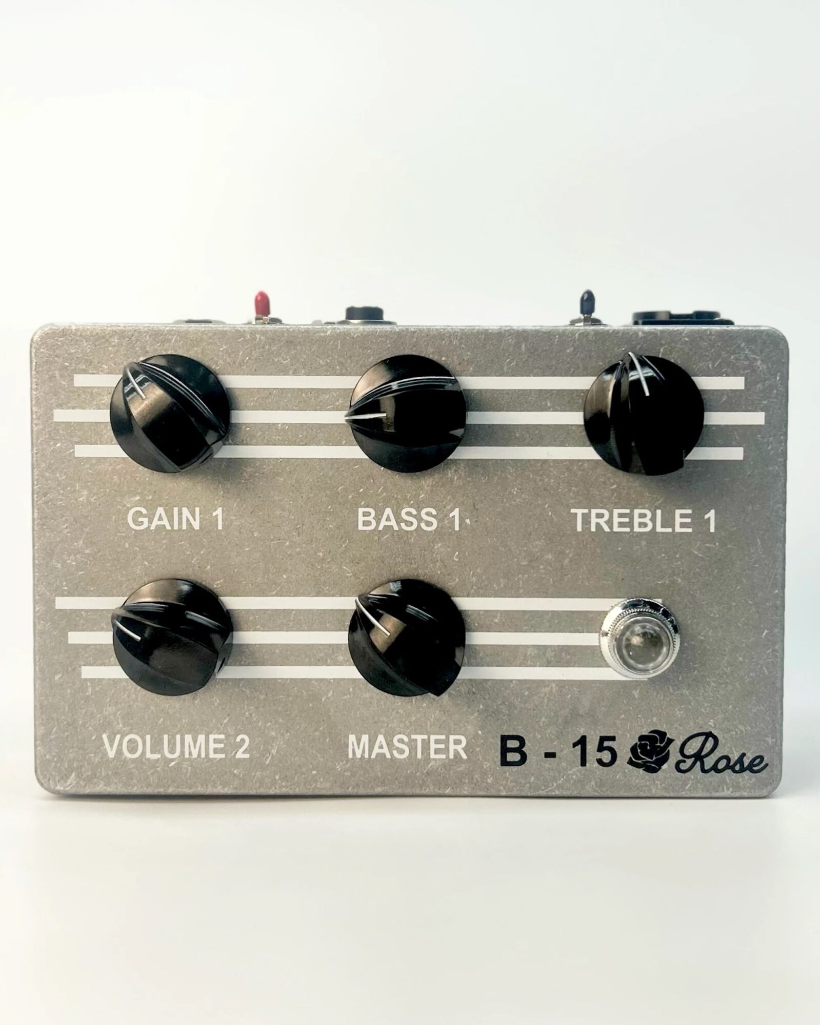 Guitar effects pedal with six black knobs labeled Gain 1, Bass 1, Treble 1, Volume 2, Master, and a silver input jack, on a white background.